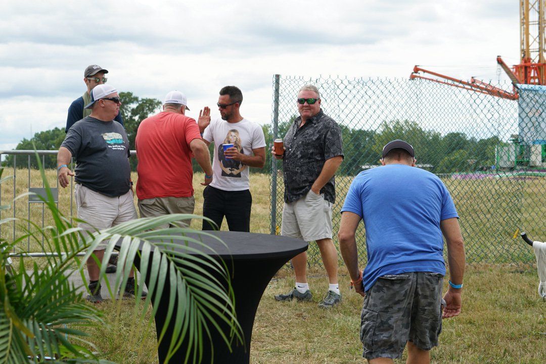 A group of men are standing around a table in a field.