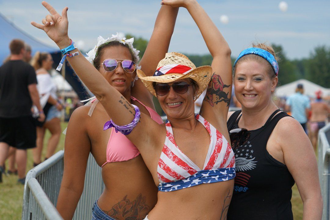 Three women are posing for a picture with their arms in the air.