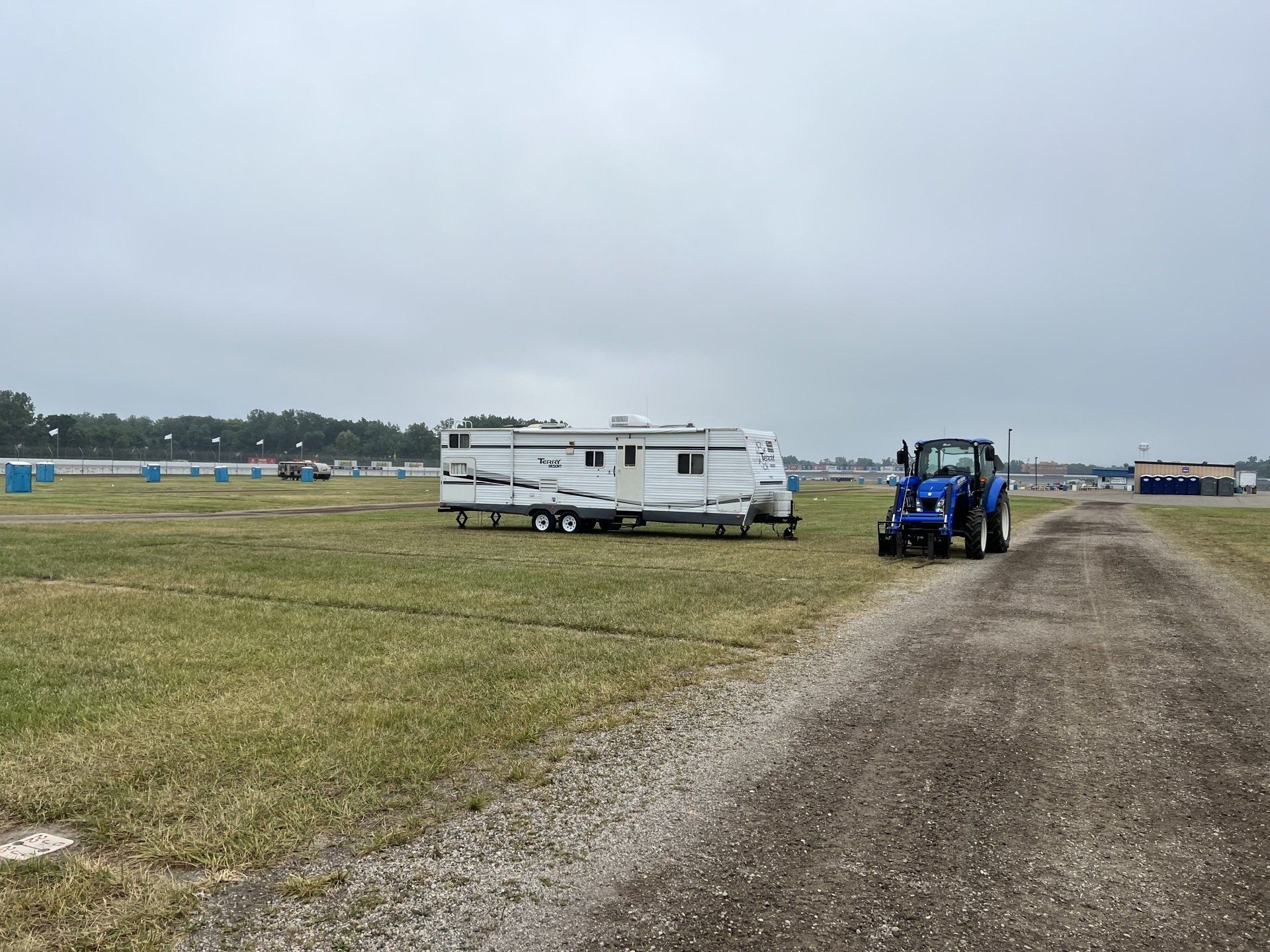 A trailer is being towed by a tractor down a dirt road.