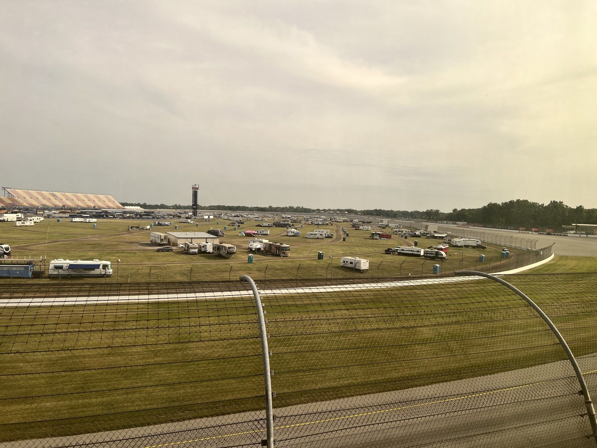 An aerial view of a race track with a lot of cars parked on the grass.