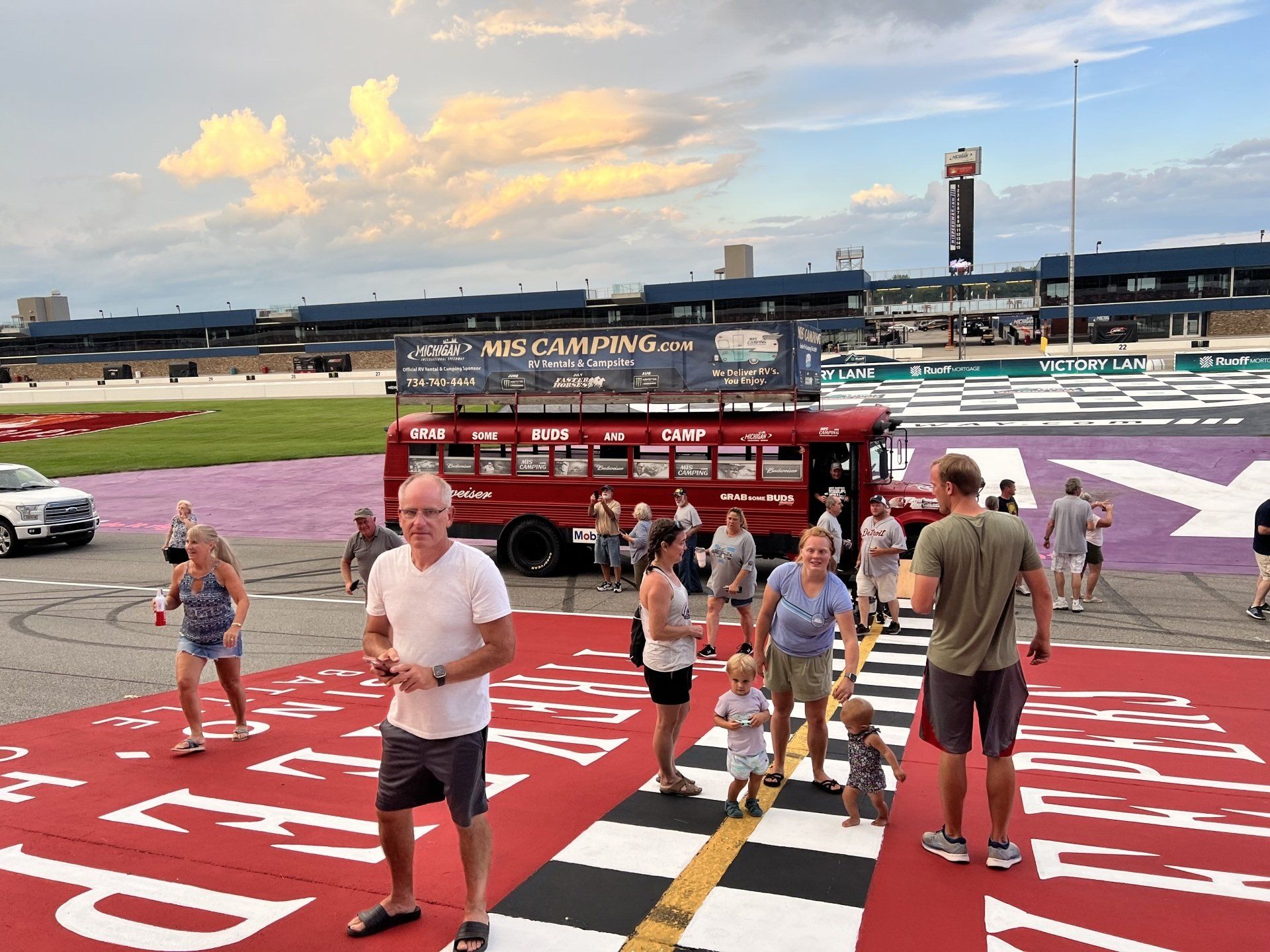 A group of people are walking across a checkered crosswalk in front of a red bus