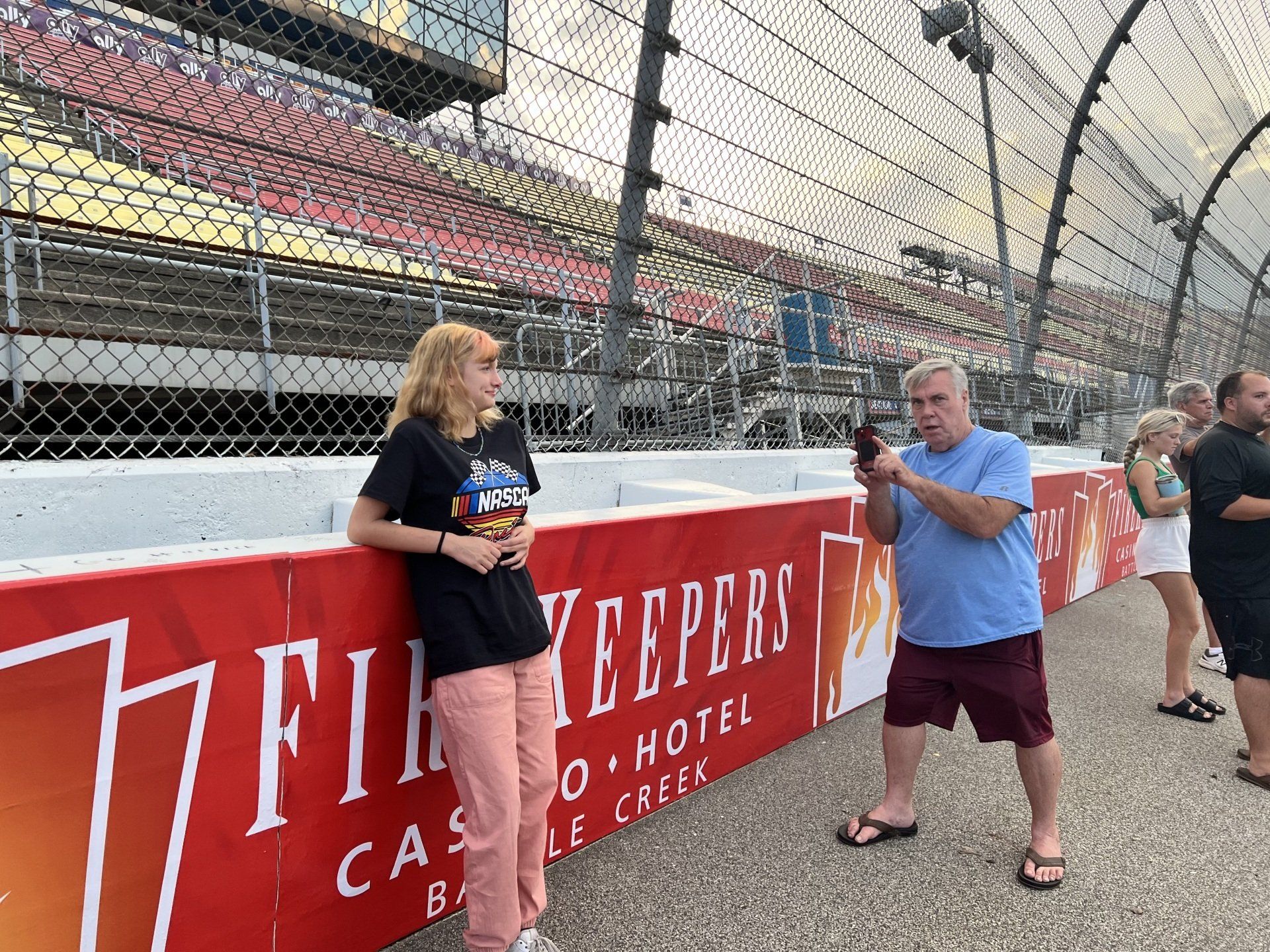 A man taking a picture of a woman in front of a sign that says fire keepers