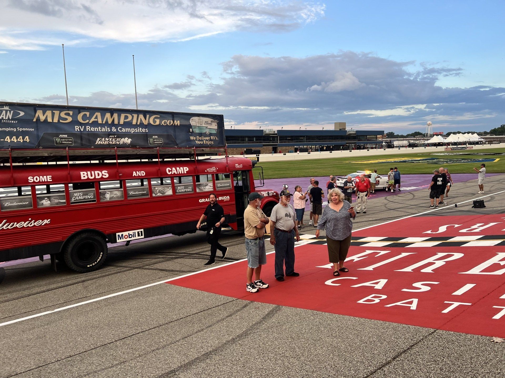 People standing in front of a red bus that says mis camping