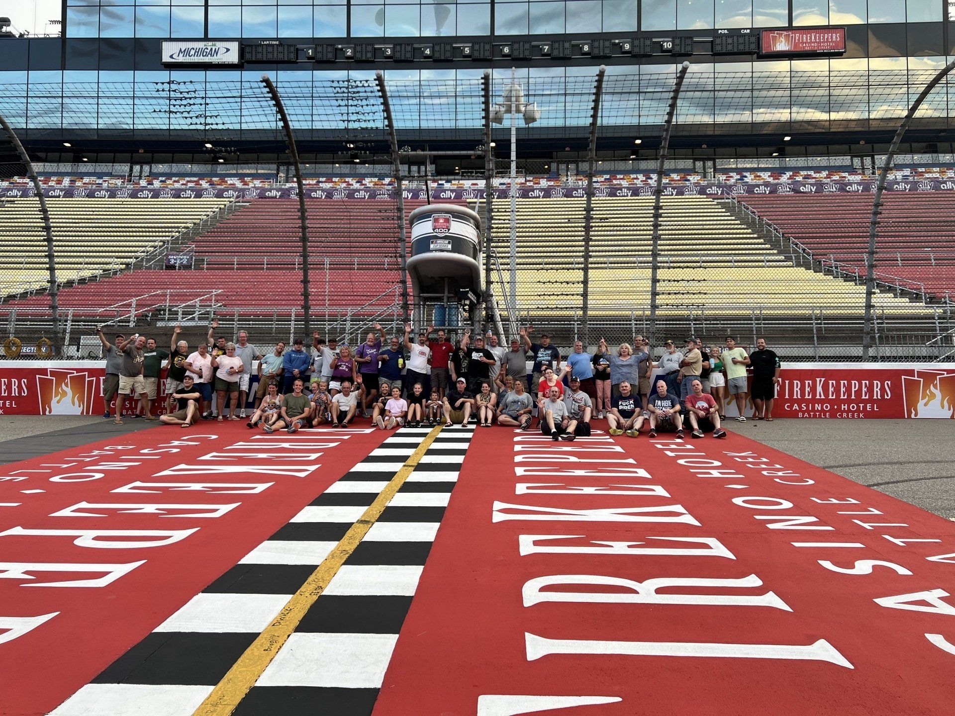 A group of people are posing for a picture on a race track