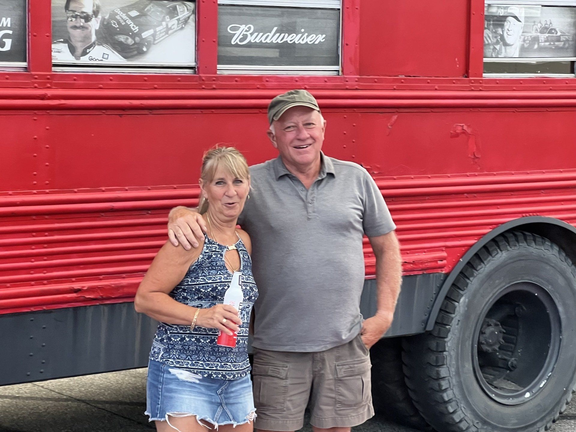 A man and a woman are standing in front of a red bus.