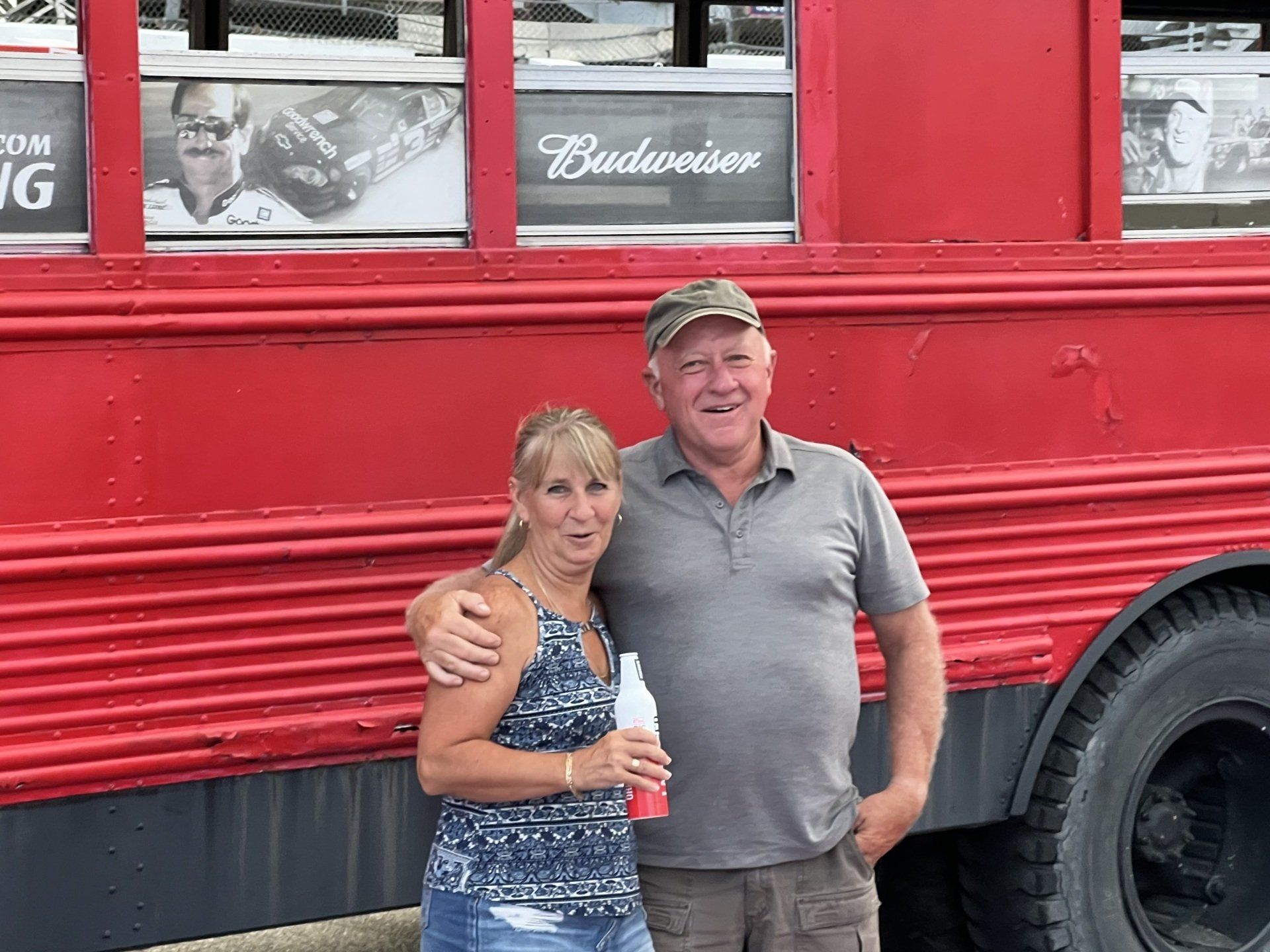A man and a woman are standing in front of a red bus.