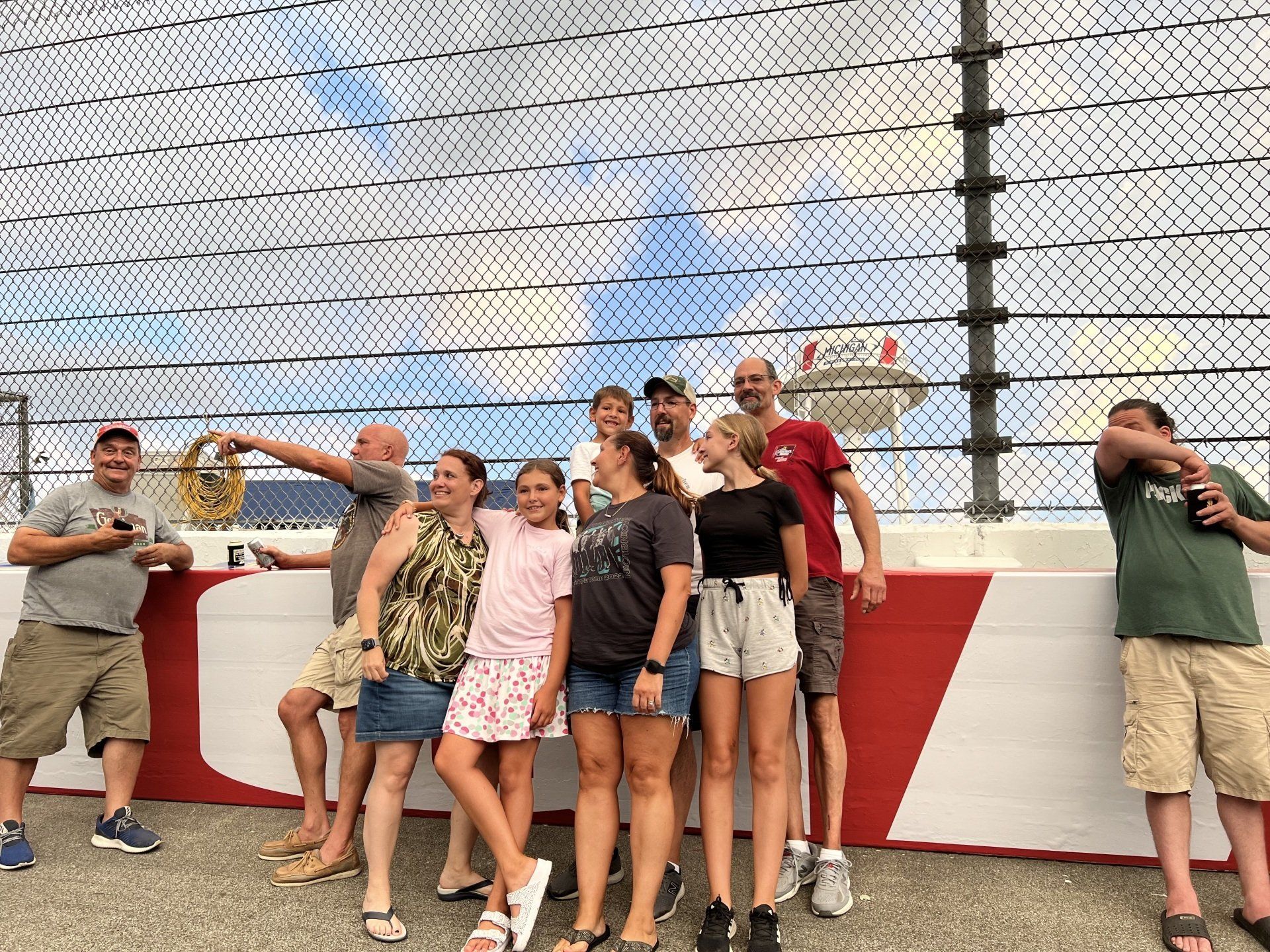 A group of people are posing for a picture in front of a fence.
