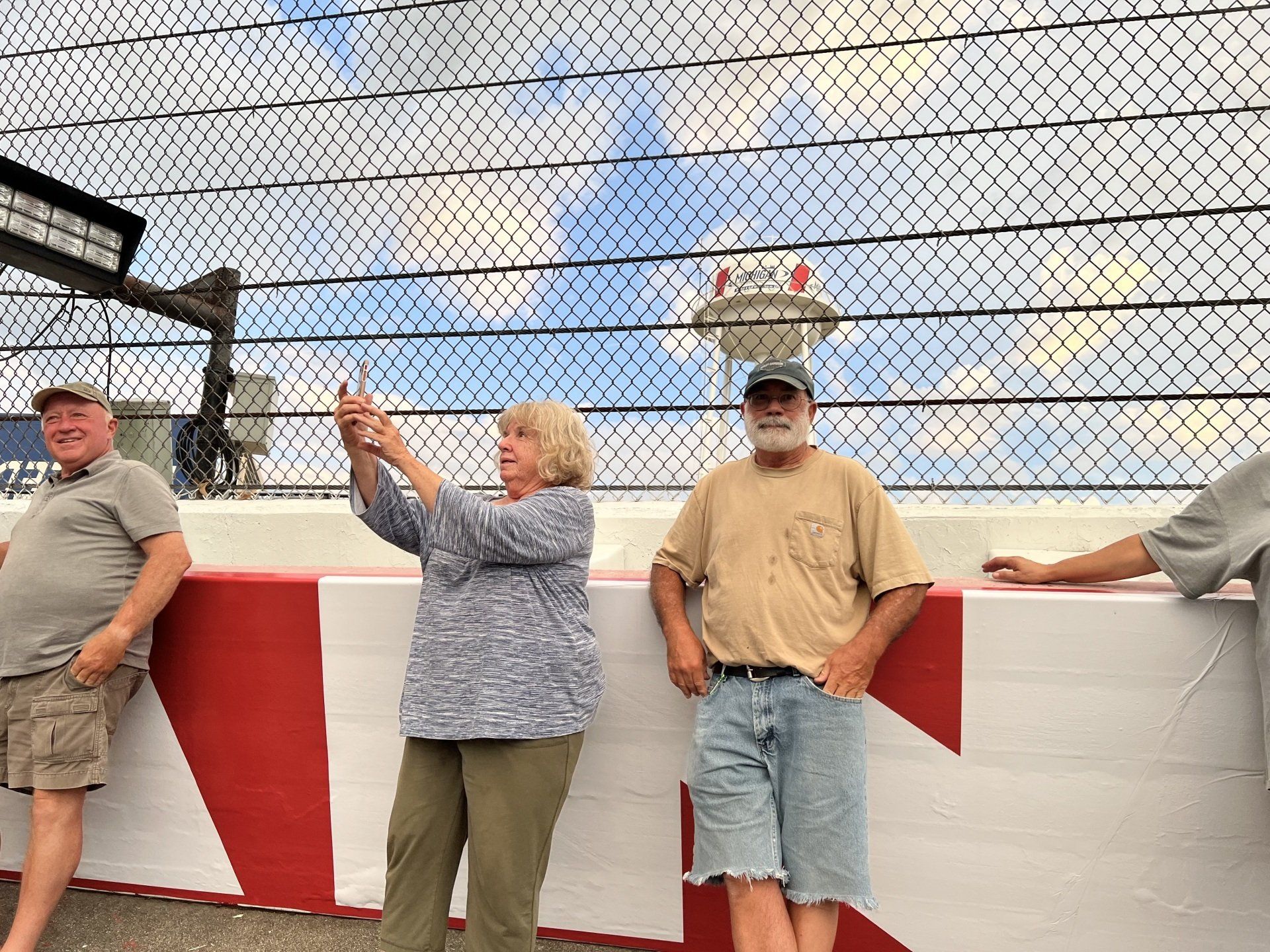 A group of people are standing next to each other in front of a fence.