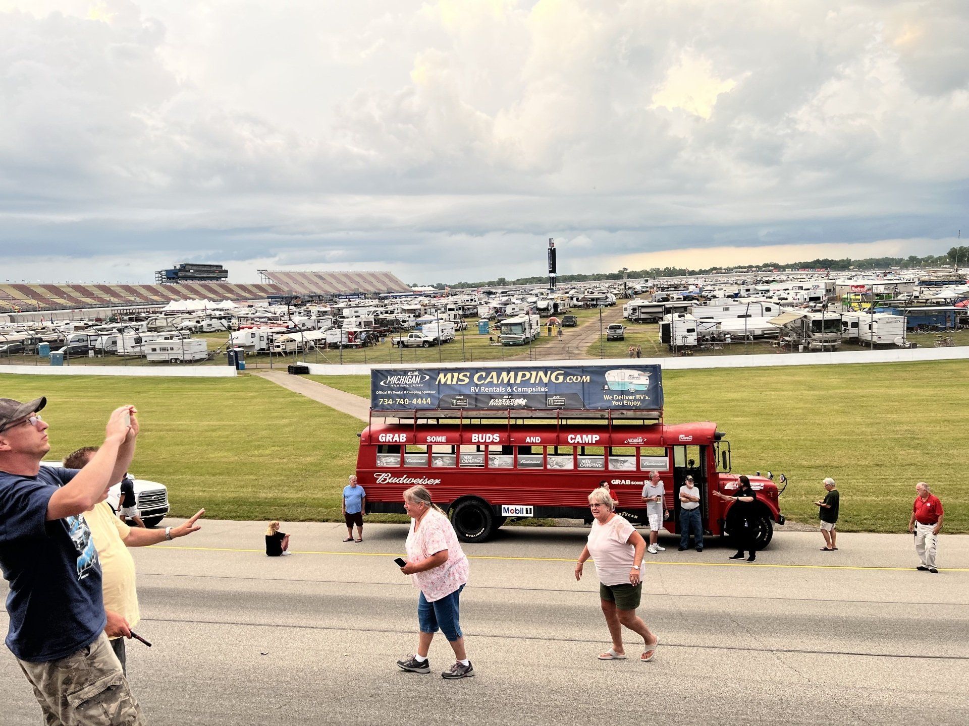 A man taking a picture of a red bus that says mini camping