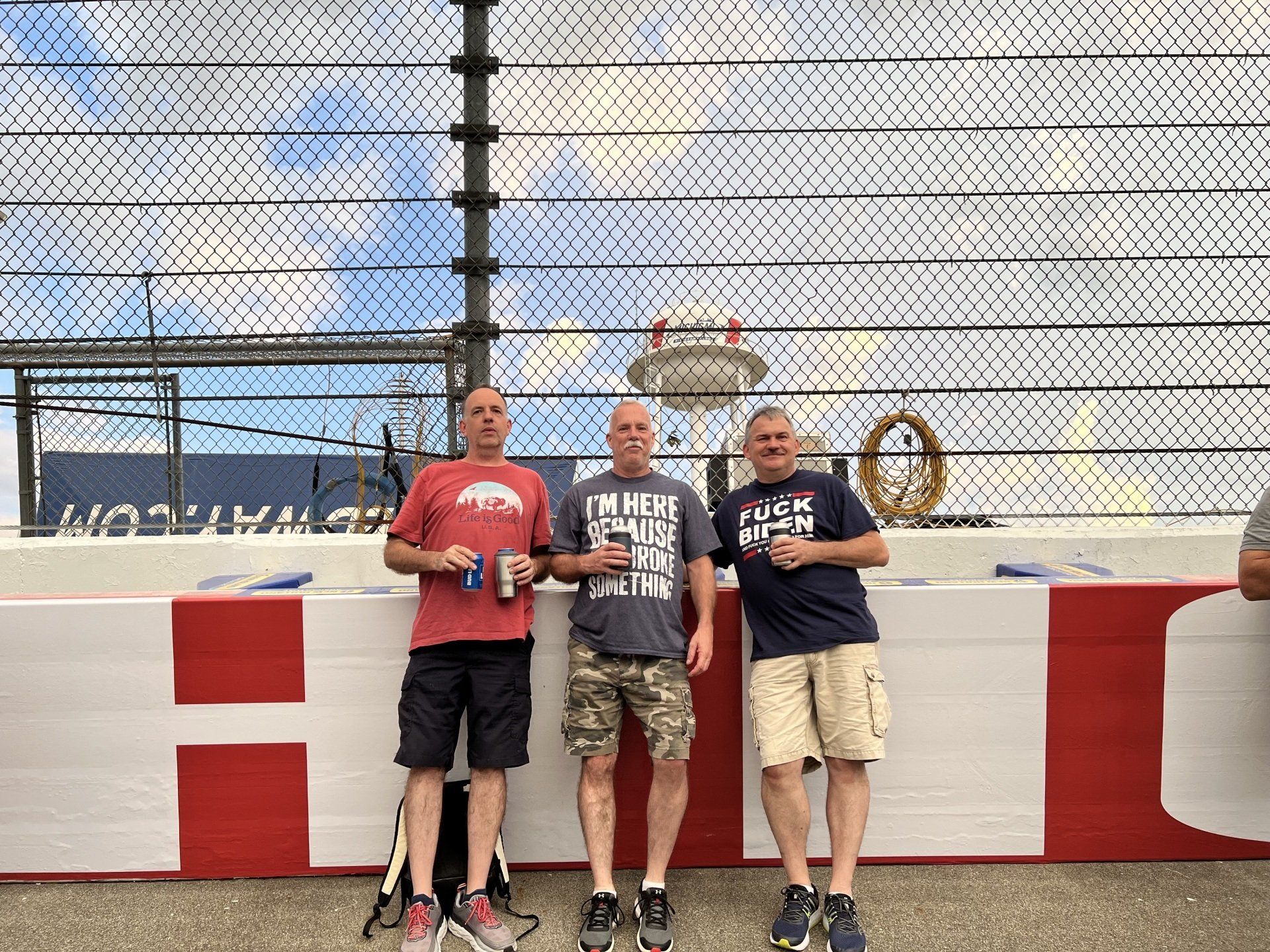Three men are standing next to each other on a race track.