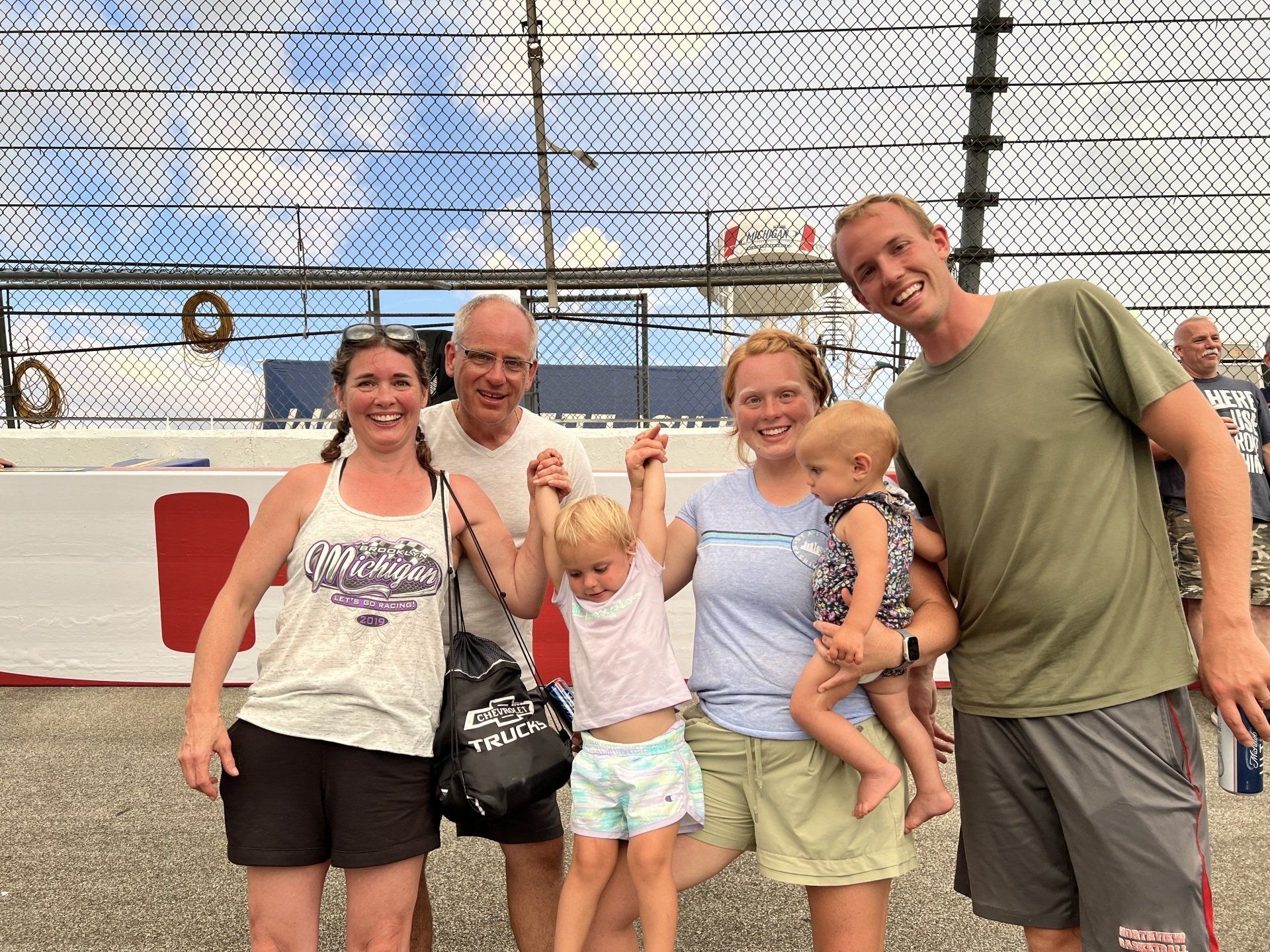 A group of people are posing for a picture in front of a race track.