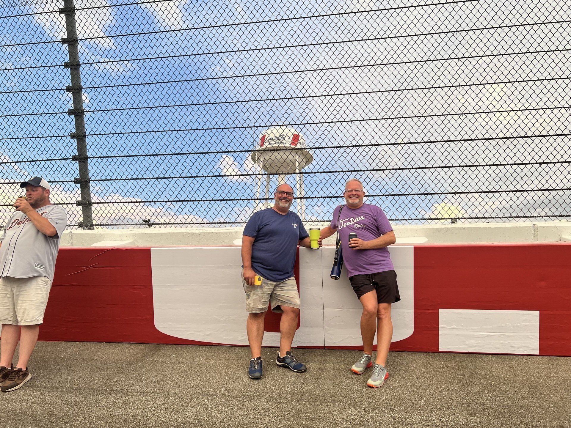 Three men are standing next to each other on a race track.