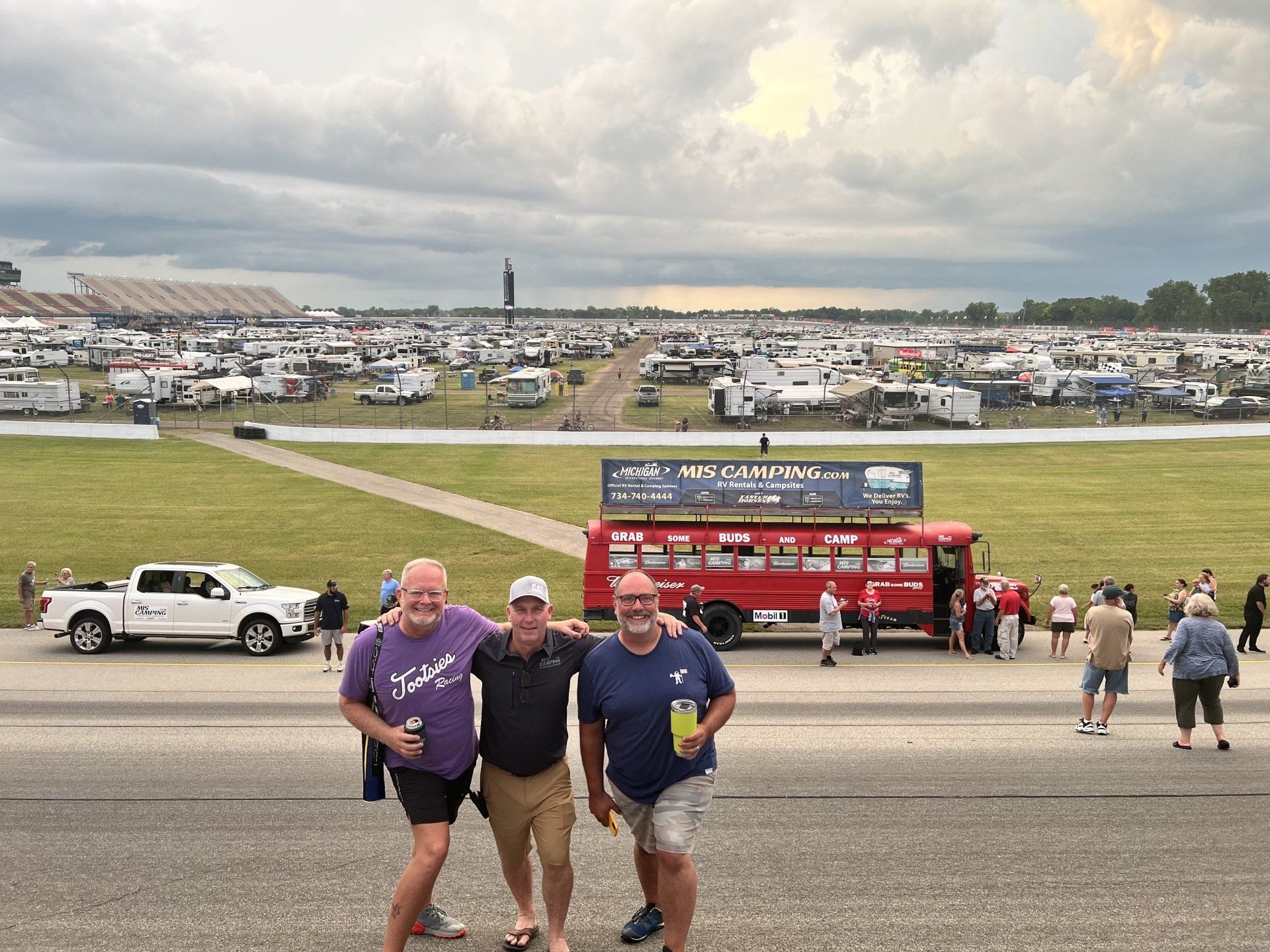 Three men are posing for a picture in front of a large field.