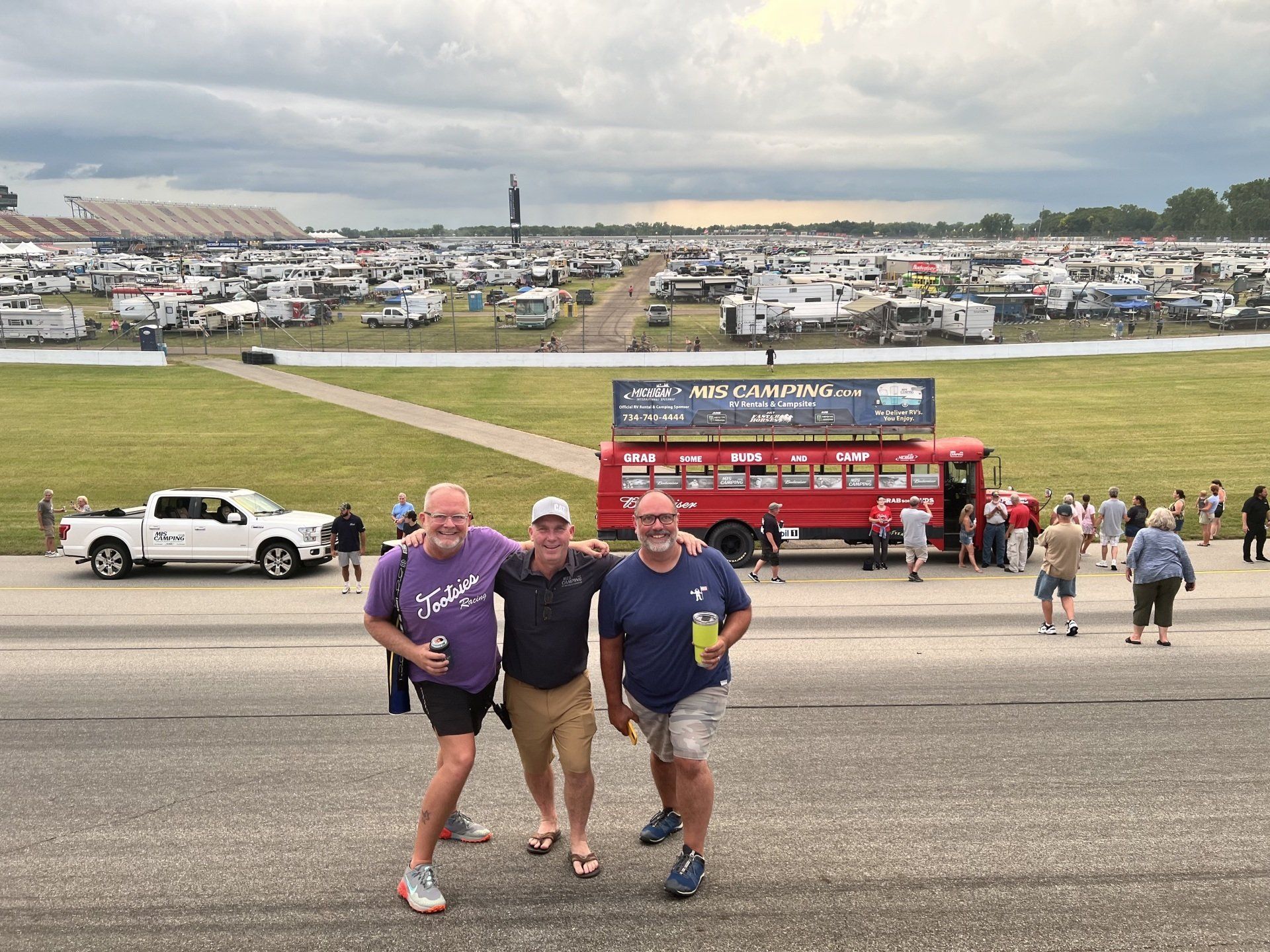 Three men are posing for a picture in front of a large field.
