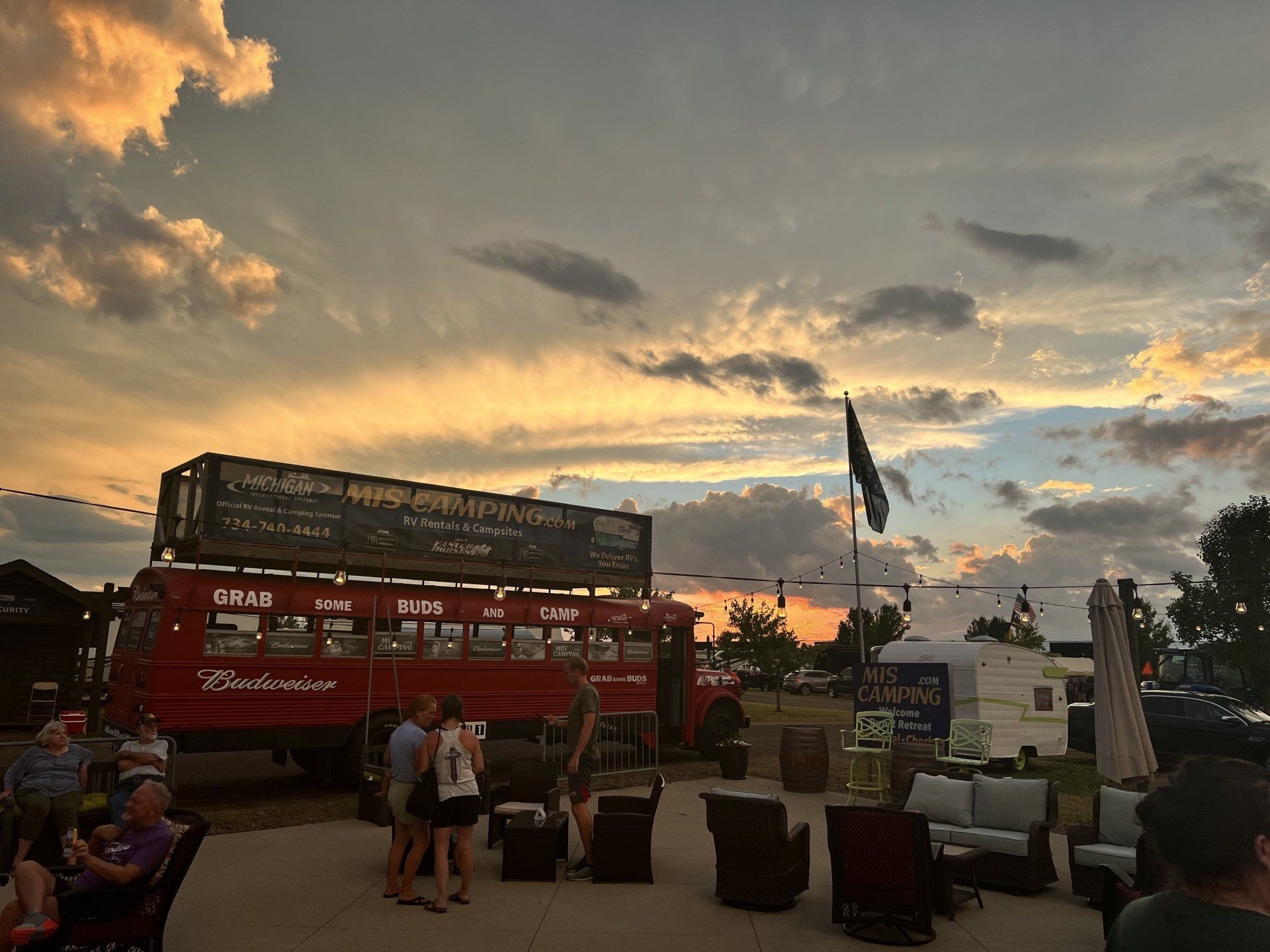 A red double decker bus is parked in front of a sunset.