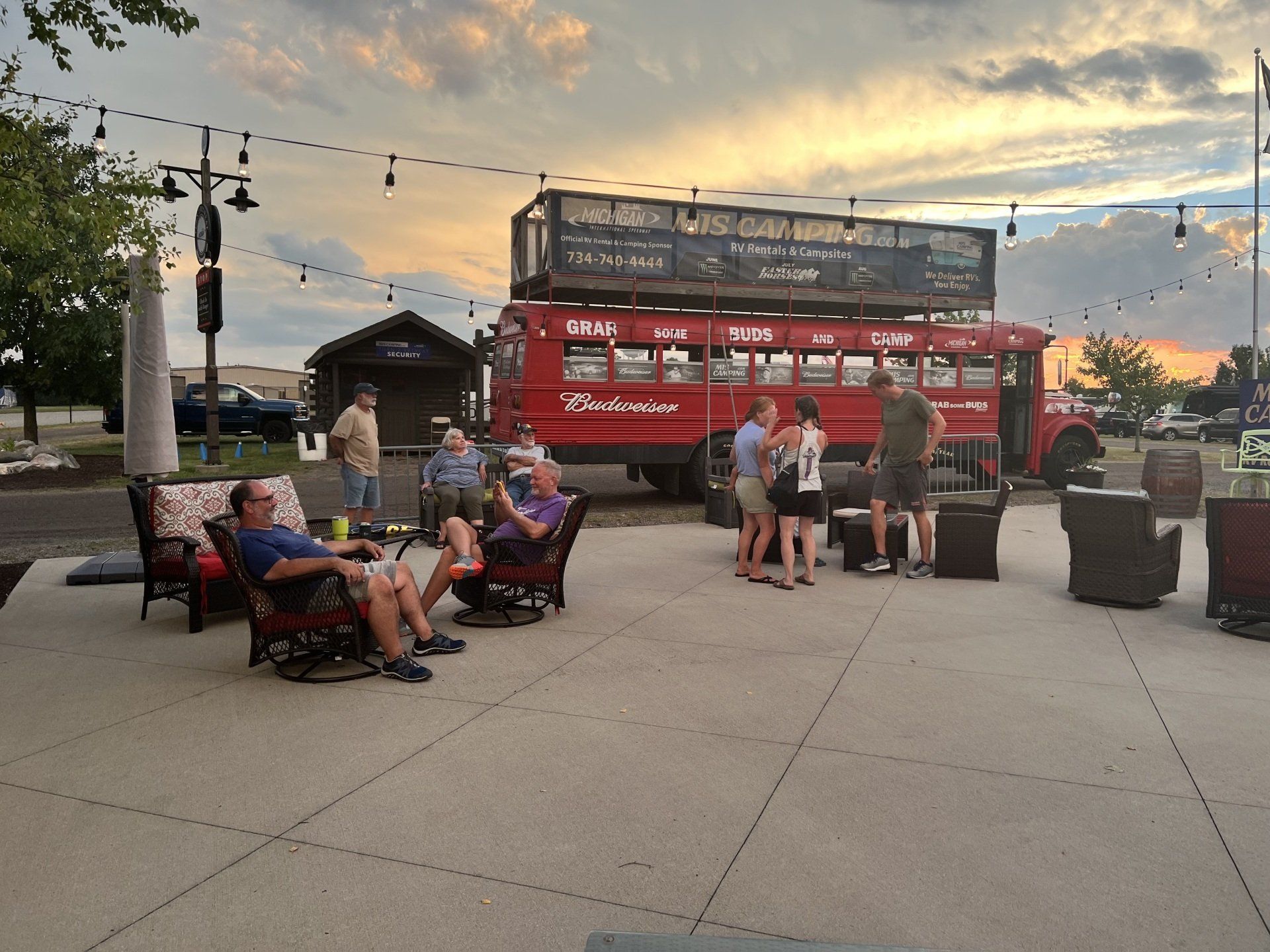 A group of people are sitting in front of a double decker bus.