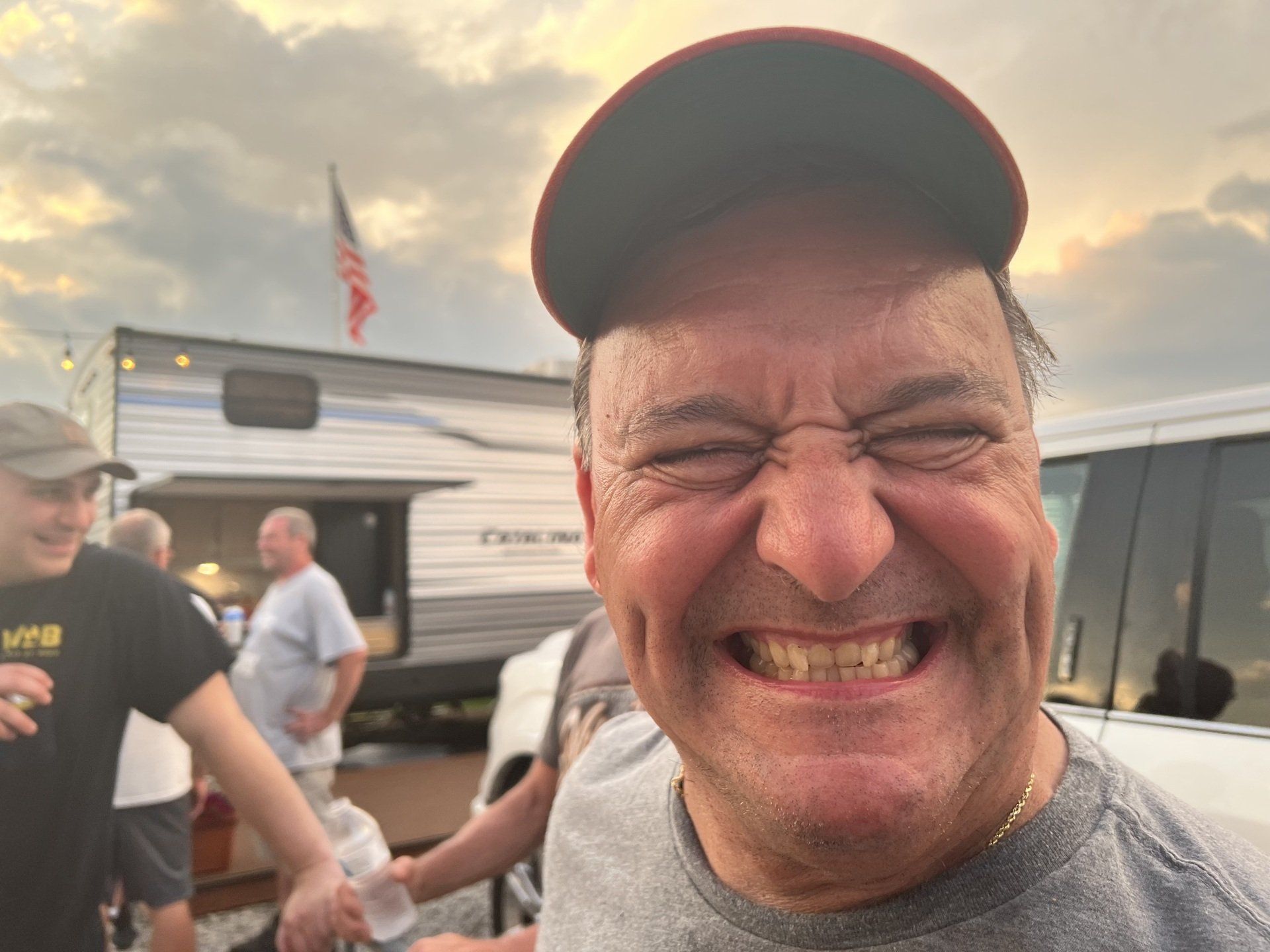 A man wearing a hat and a gray shirt is making a funny face