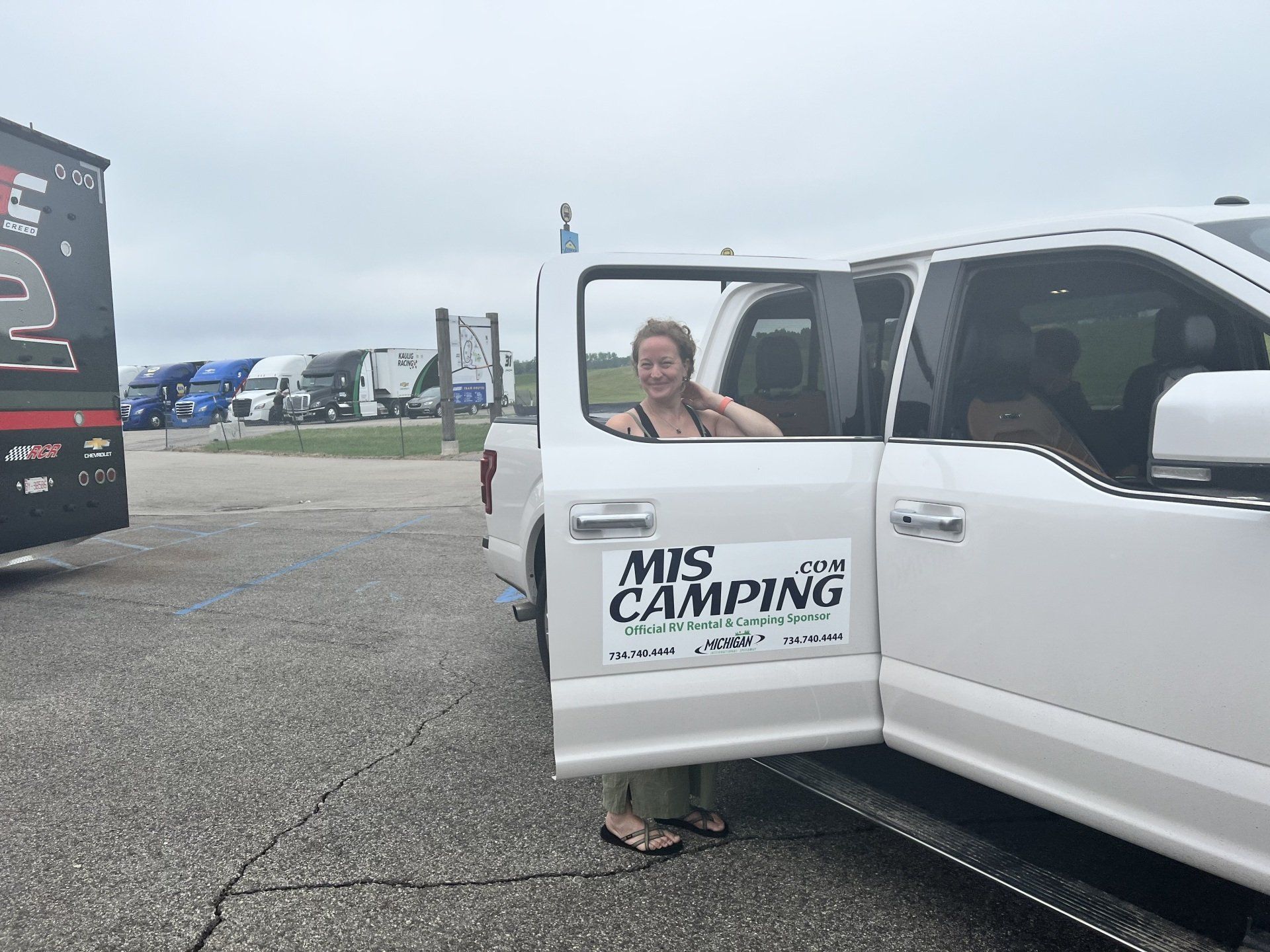 A woman is standing next to a white truck with the door open.