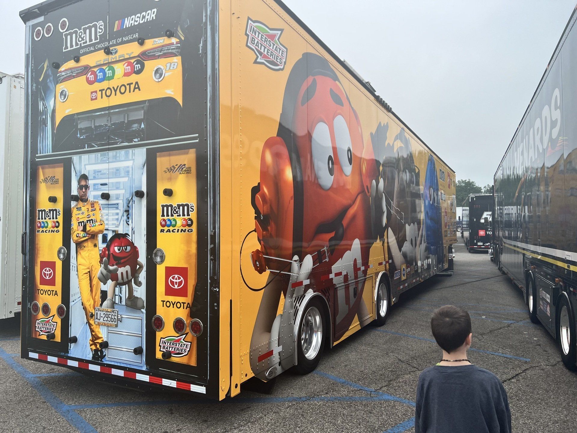 A boy is standing in front of a m & m 's truck
