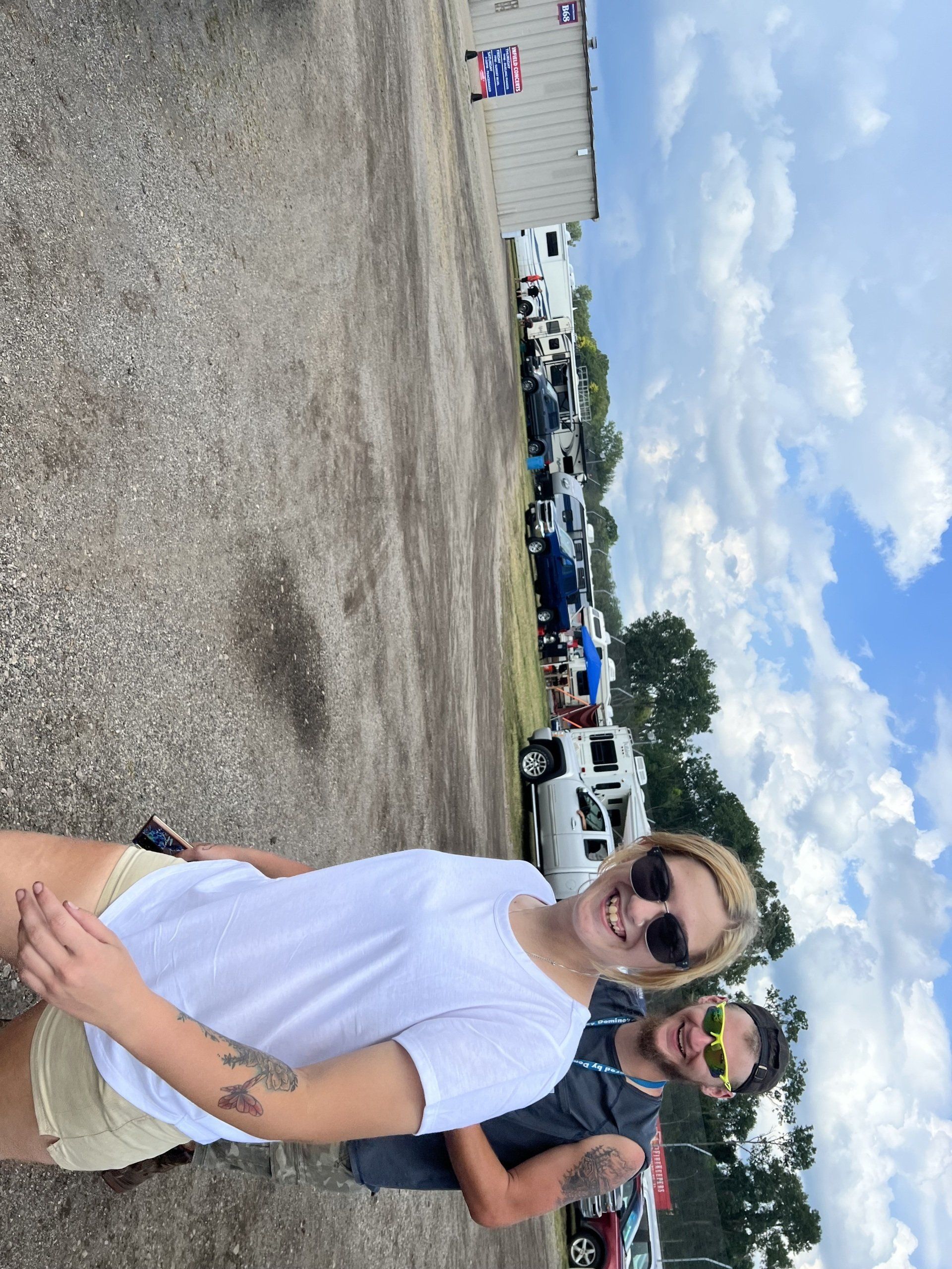 A man and a woman are posing for a picture in a parking lot