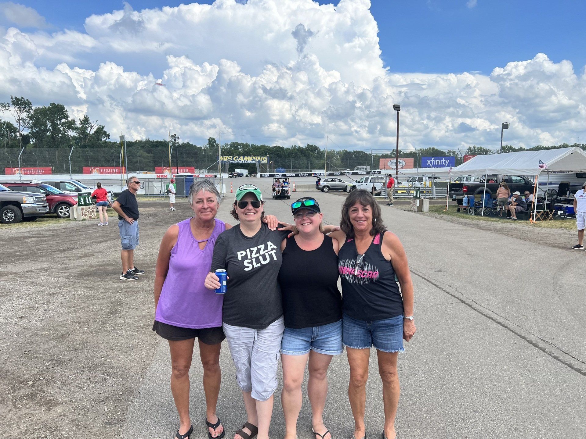 Four women posing for a picture with one wearing a pizza shirt