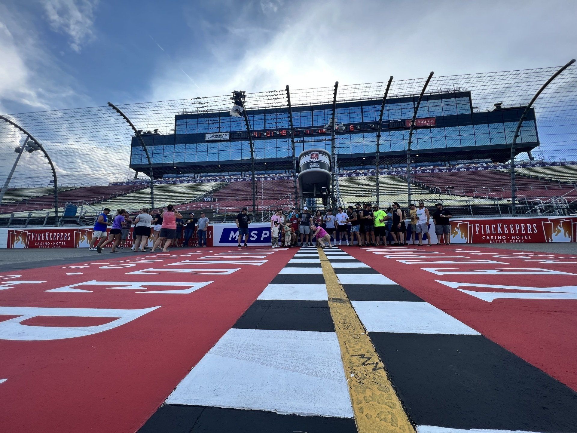 A group of people are standing on a race track in front of a large building.