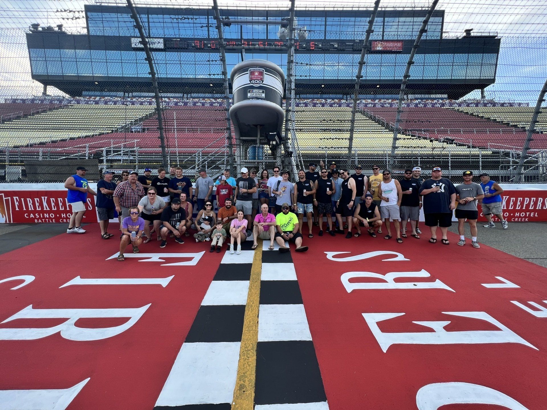 A group of people are posing for a picture in front of a race track.