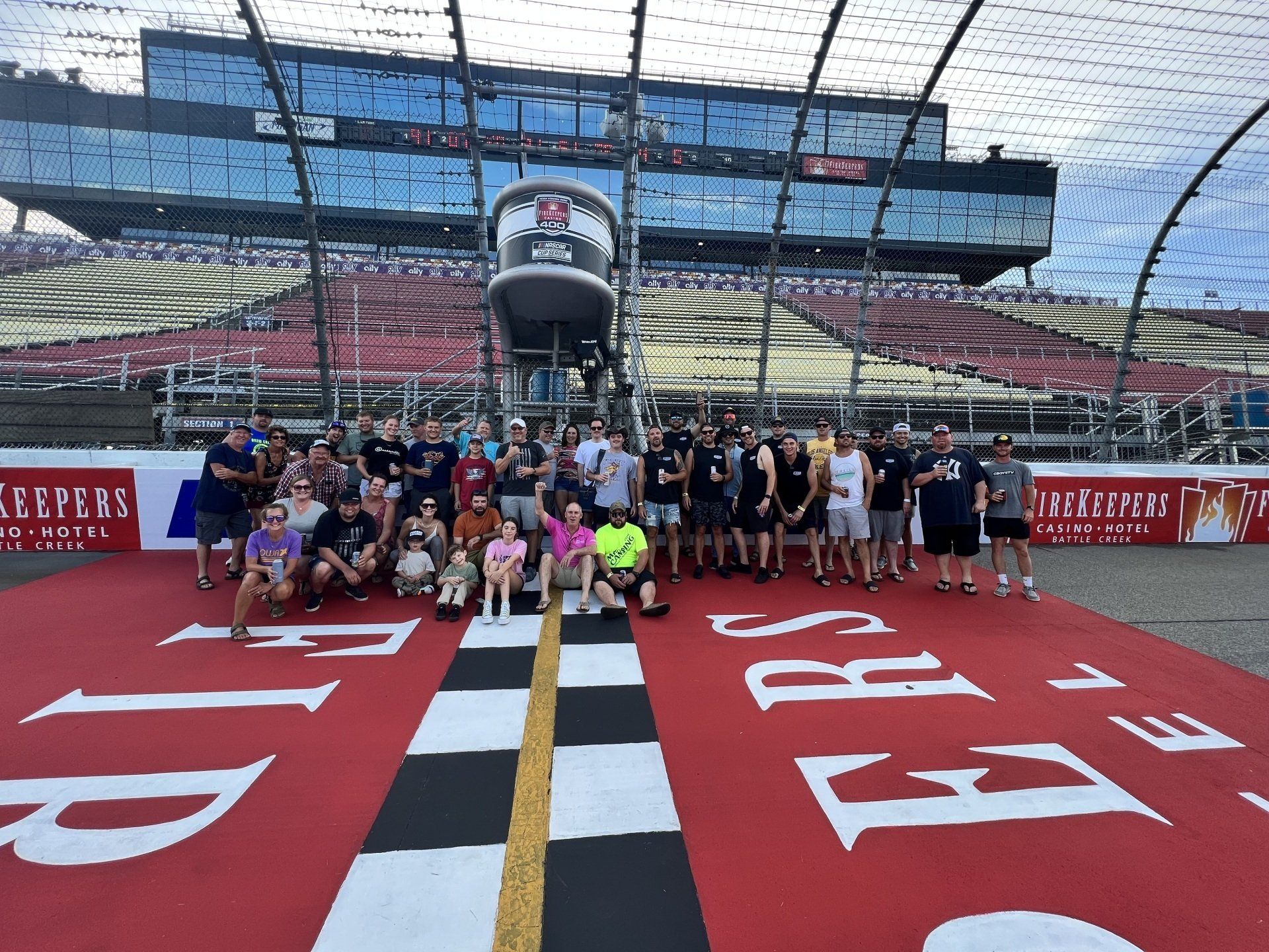 A group of people are posing for a picture in front of a race track.