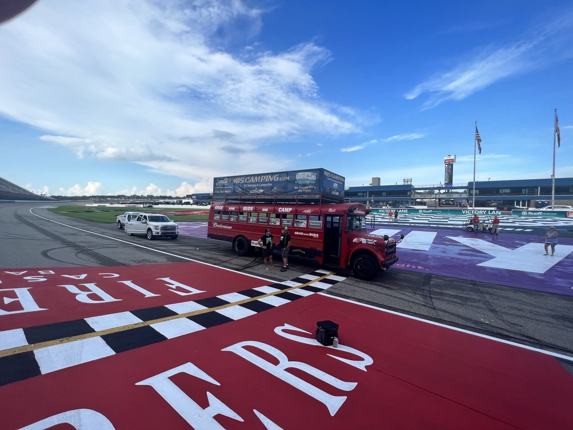 A red double decker bus is parked on a race track
