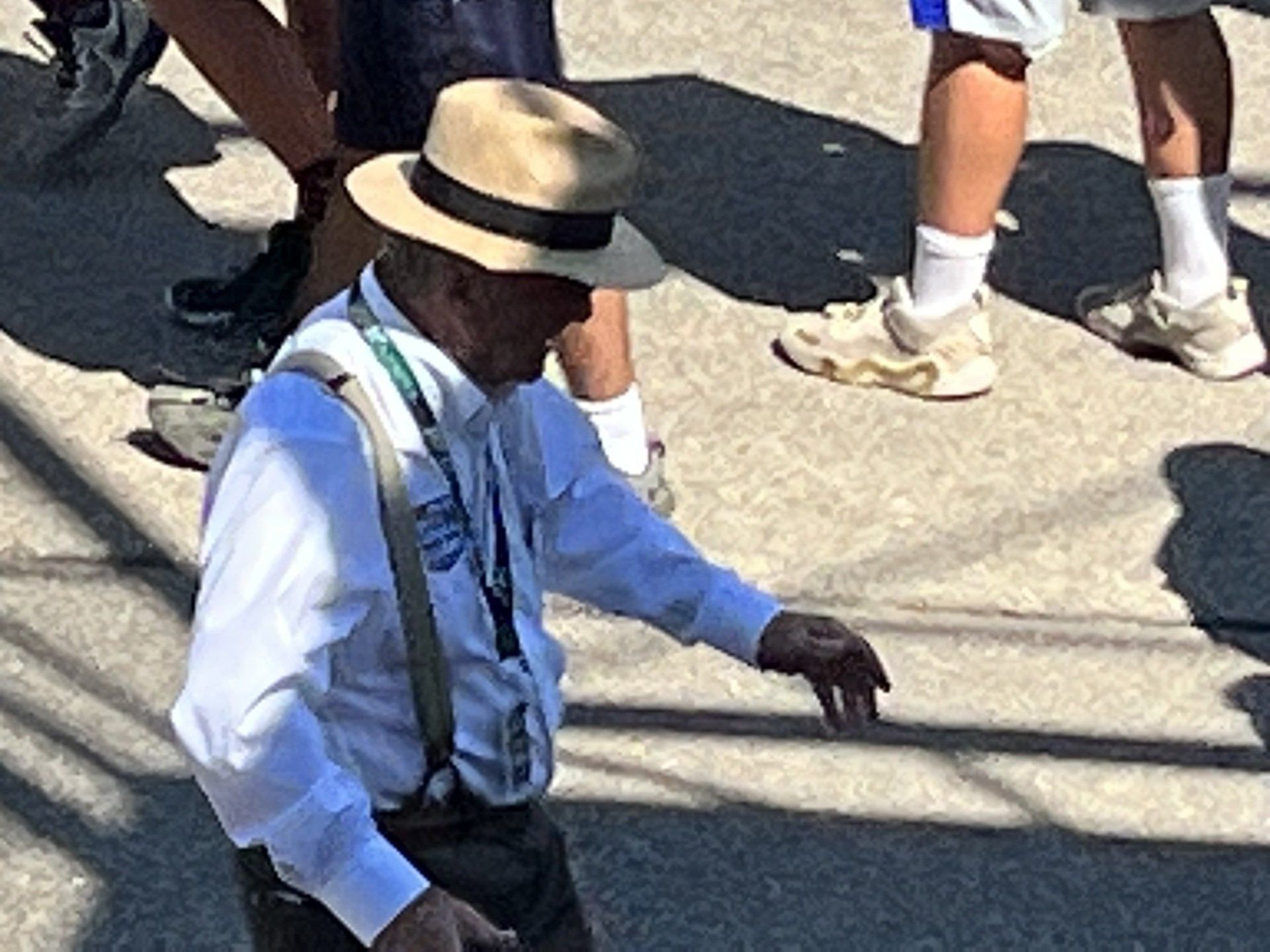 A man wearing a hat and suspenders is walking down the street