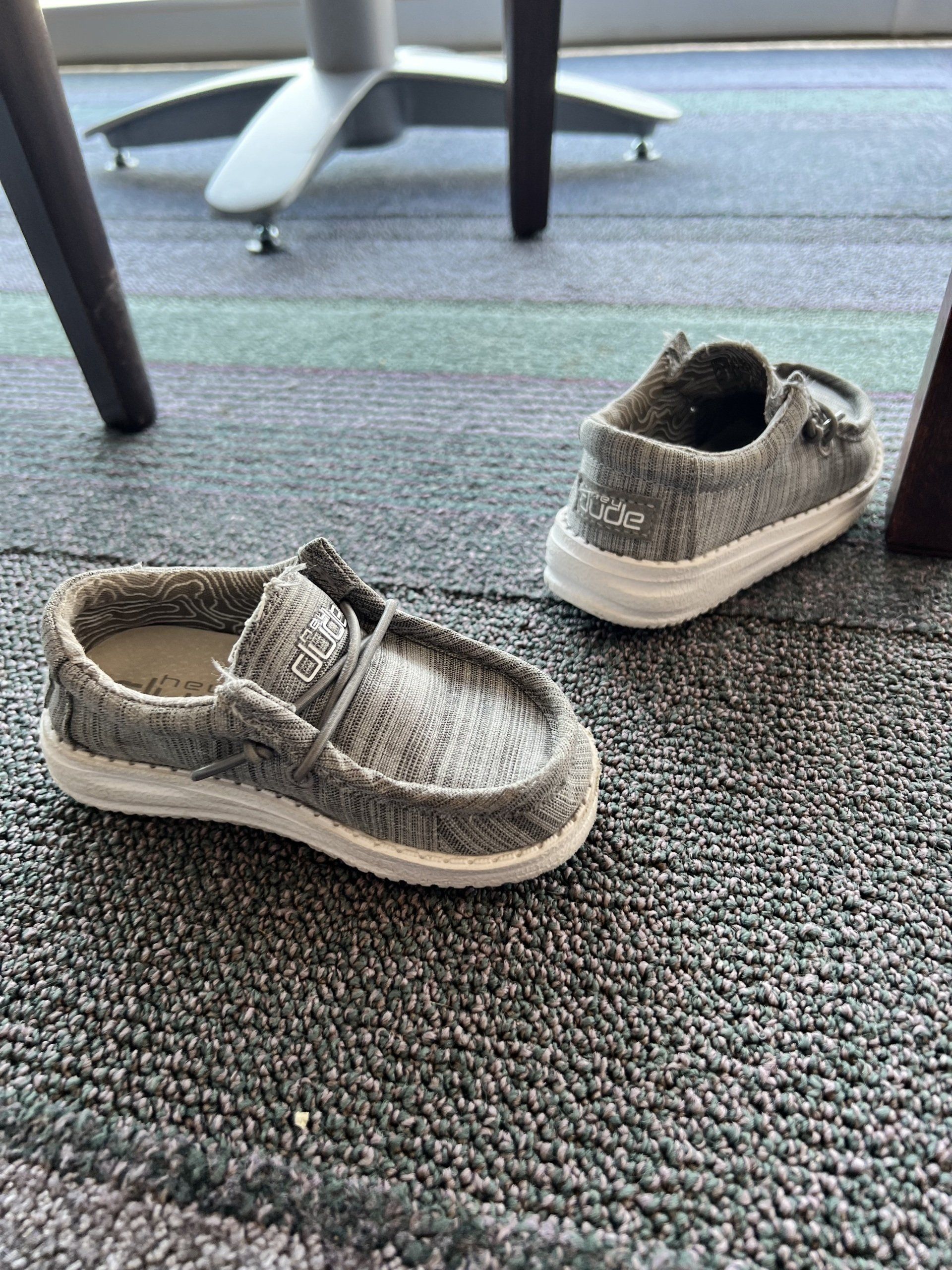 A pair of shoes are sitting on a carpet next to a table.