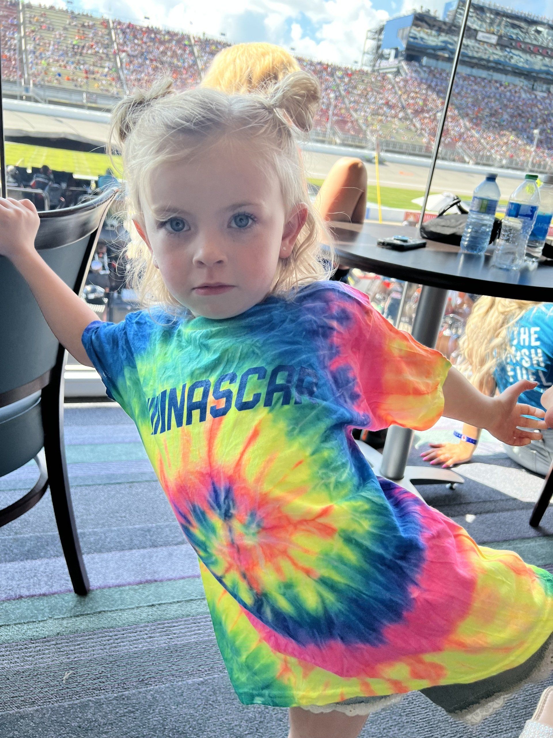 A little girl wearing a tie dye shirt that says nascar