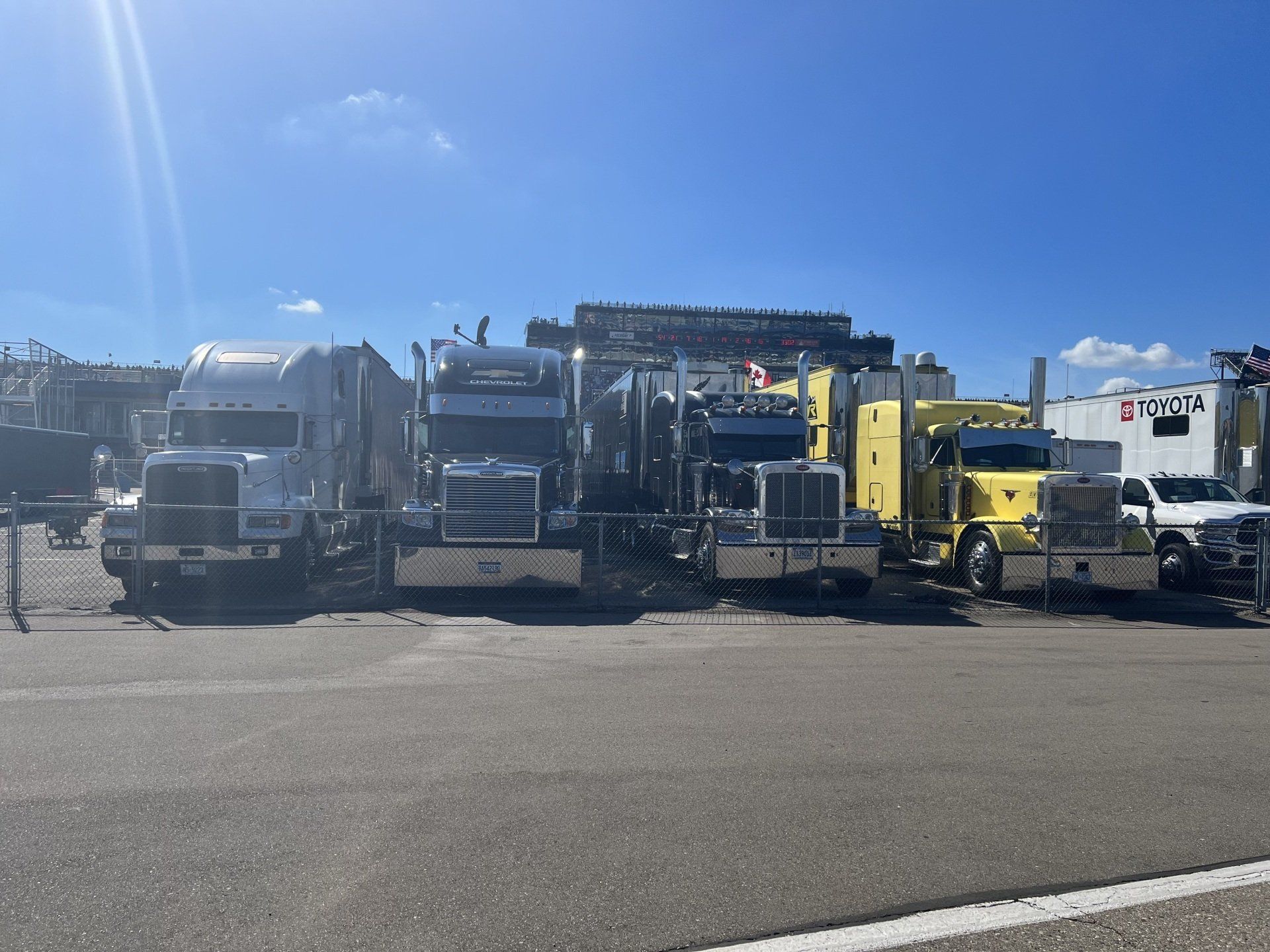 A row of semi trucks are parked in a parking lot.