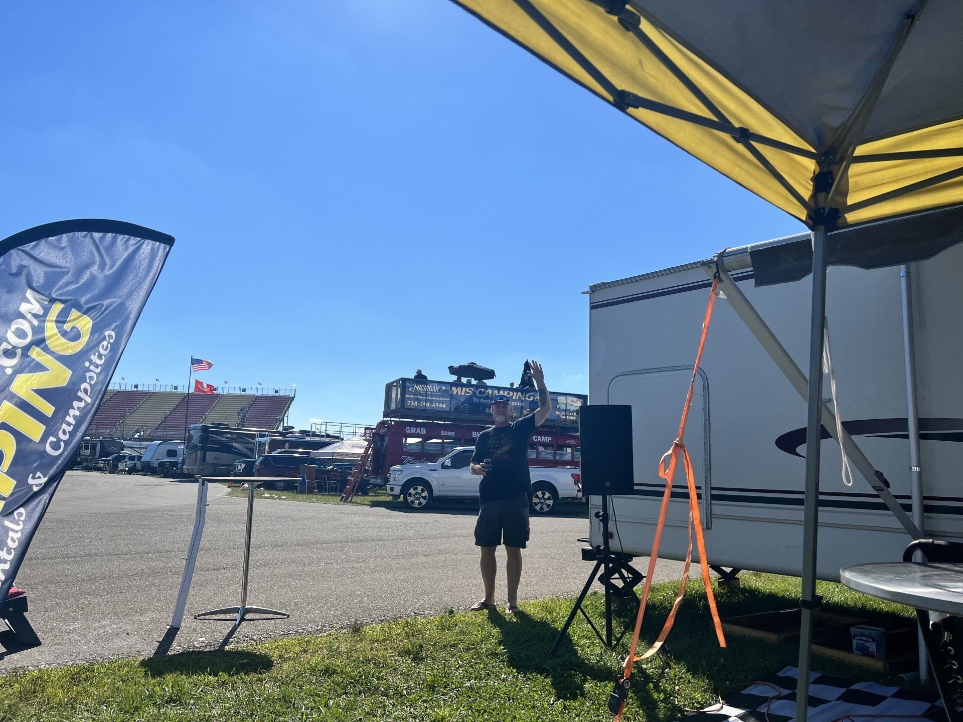 A man stands under an umbrella in front of a sign that says camping