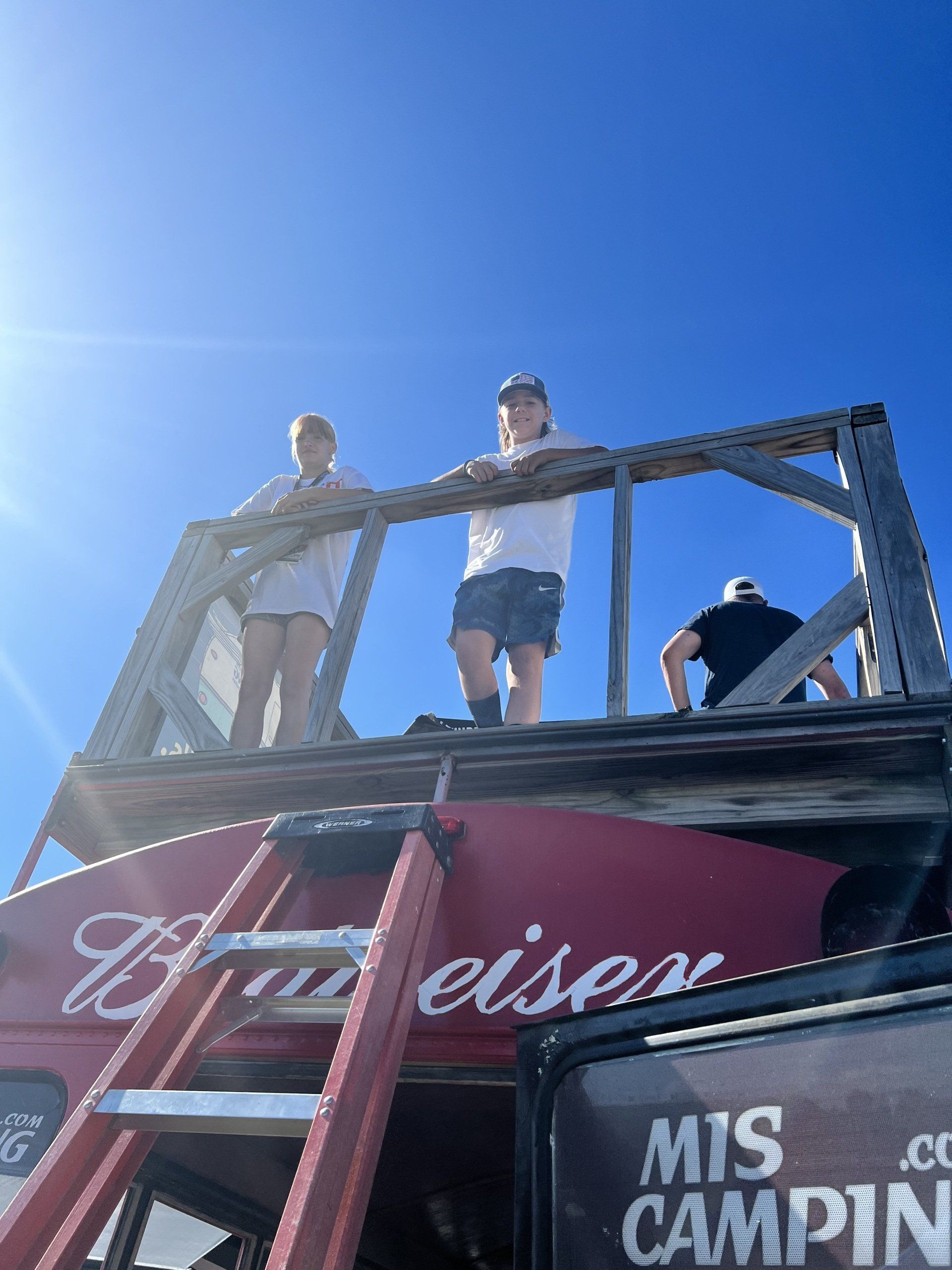 Two people standing on top of a budweiser sign