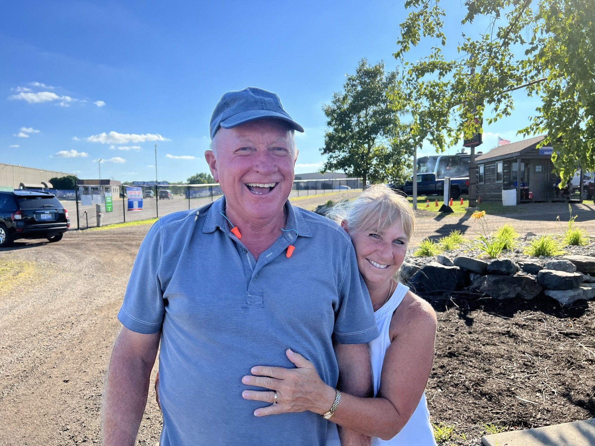 A man and a woman are posing for a picture and the woman is hugging the man