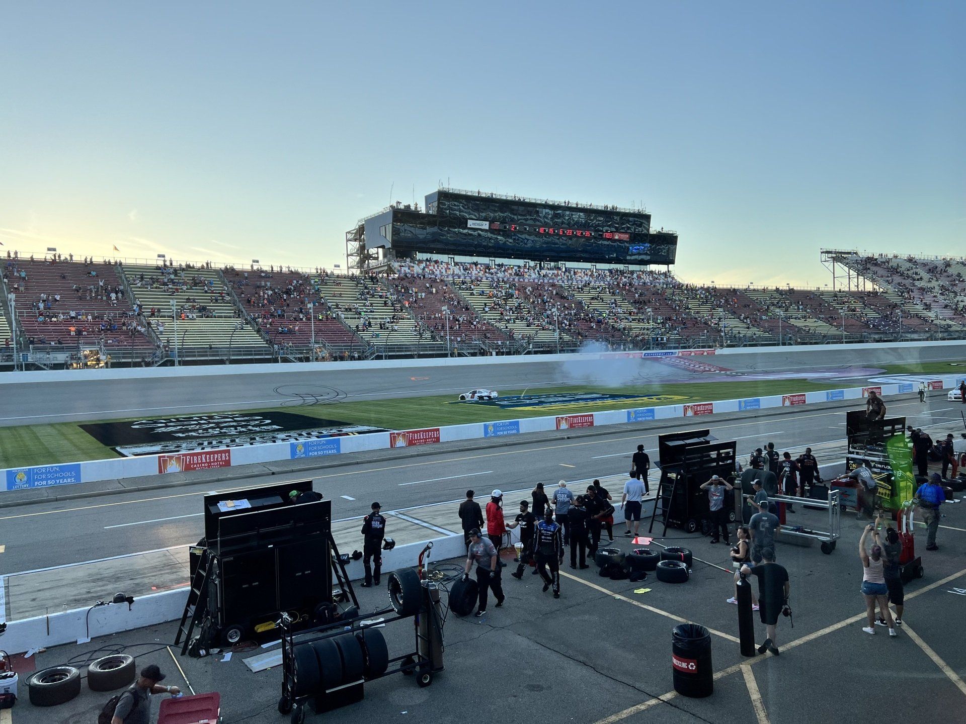 A group of people are standing on the side of a race track.