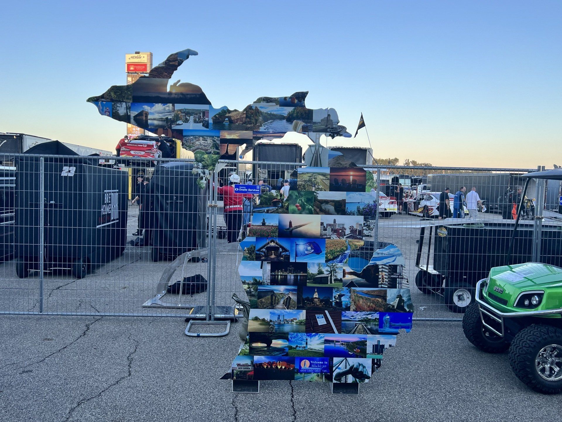 A green golf cart is parked in front of a fence with pictures on it