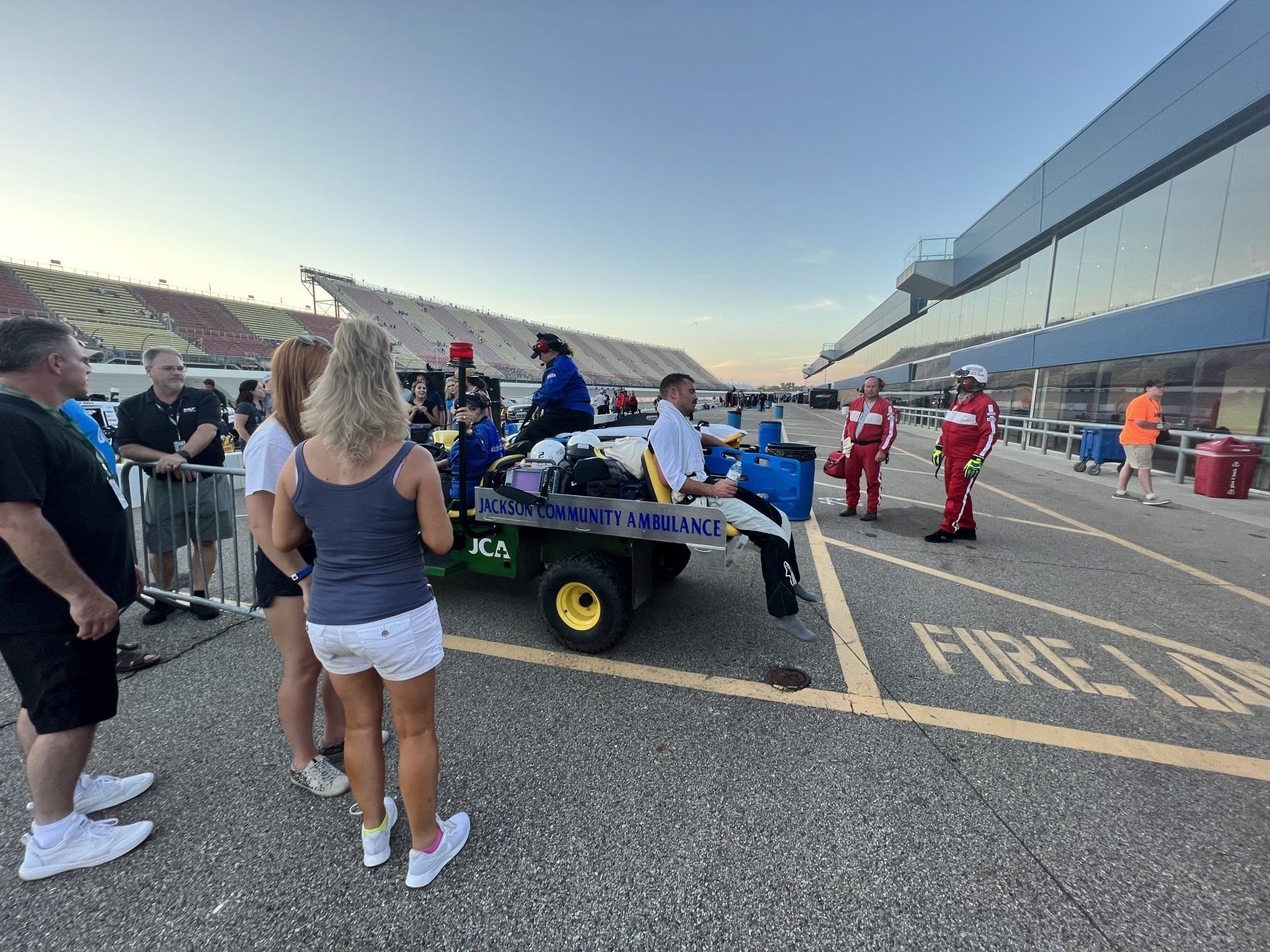 A group of people are standing around an ambulance in a parking lot.
