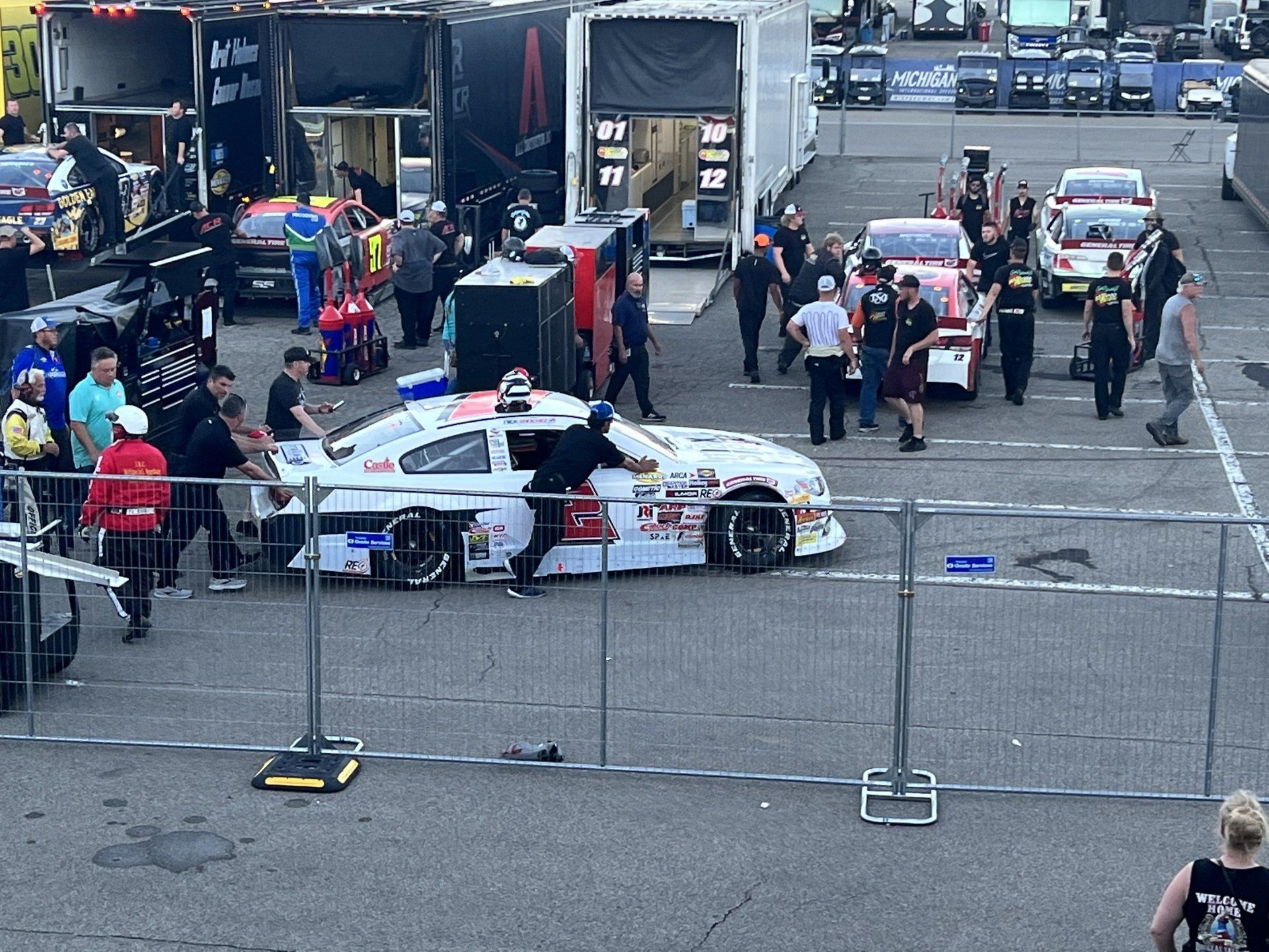 A group of people are standing around a race car in a parking lot