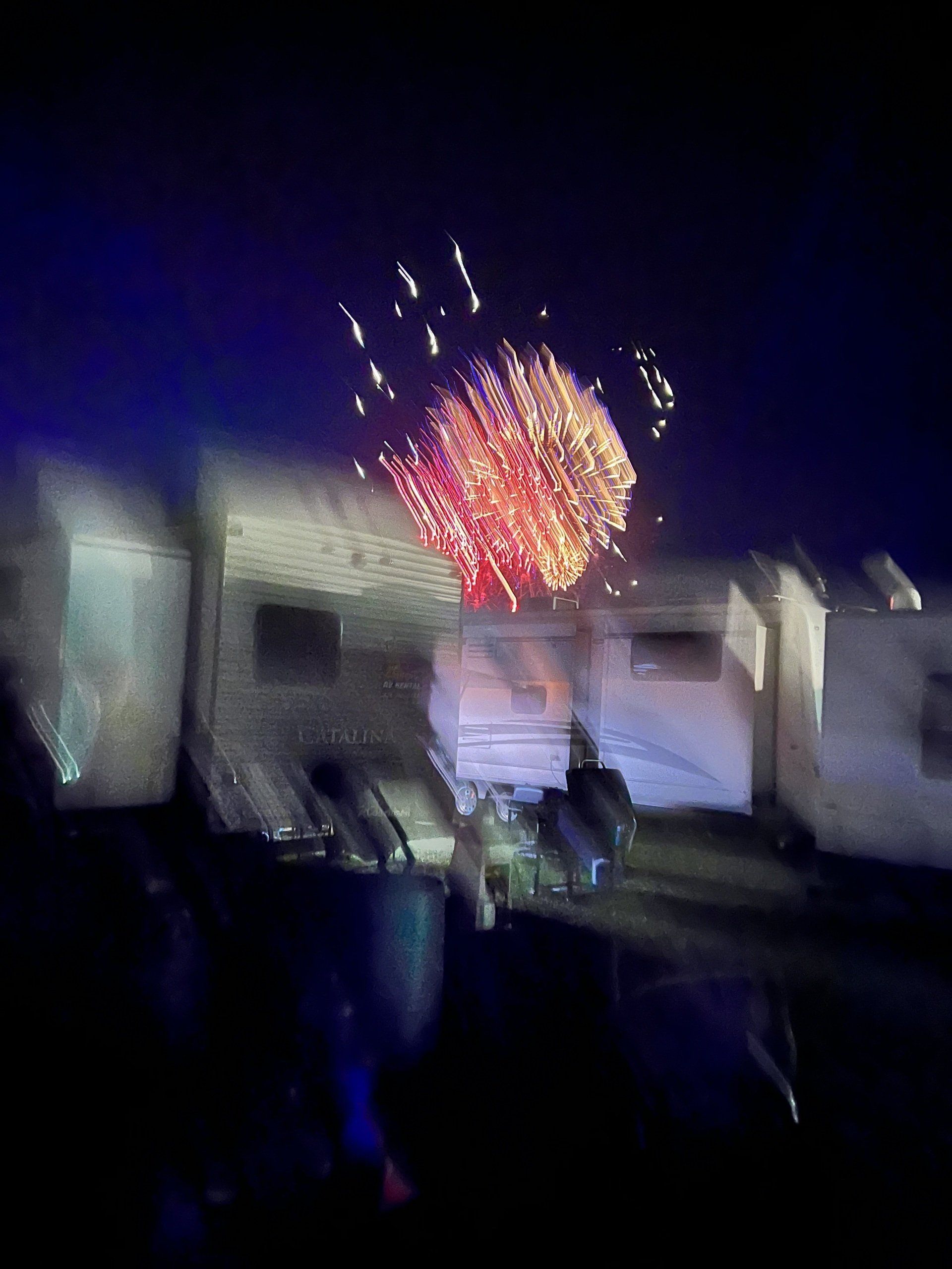 A fireworks display is taking place in front of a row of rvs.