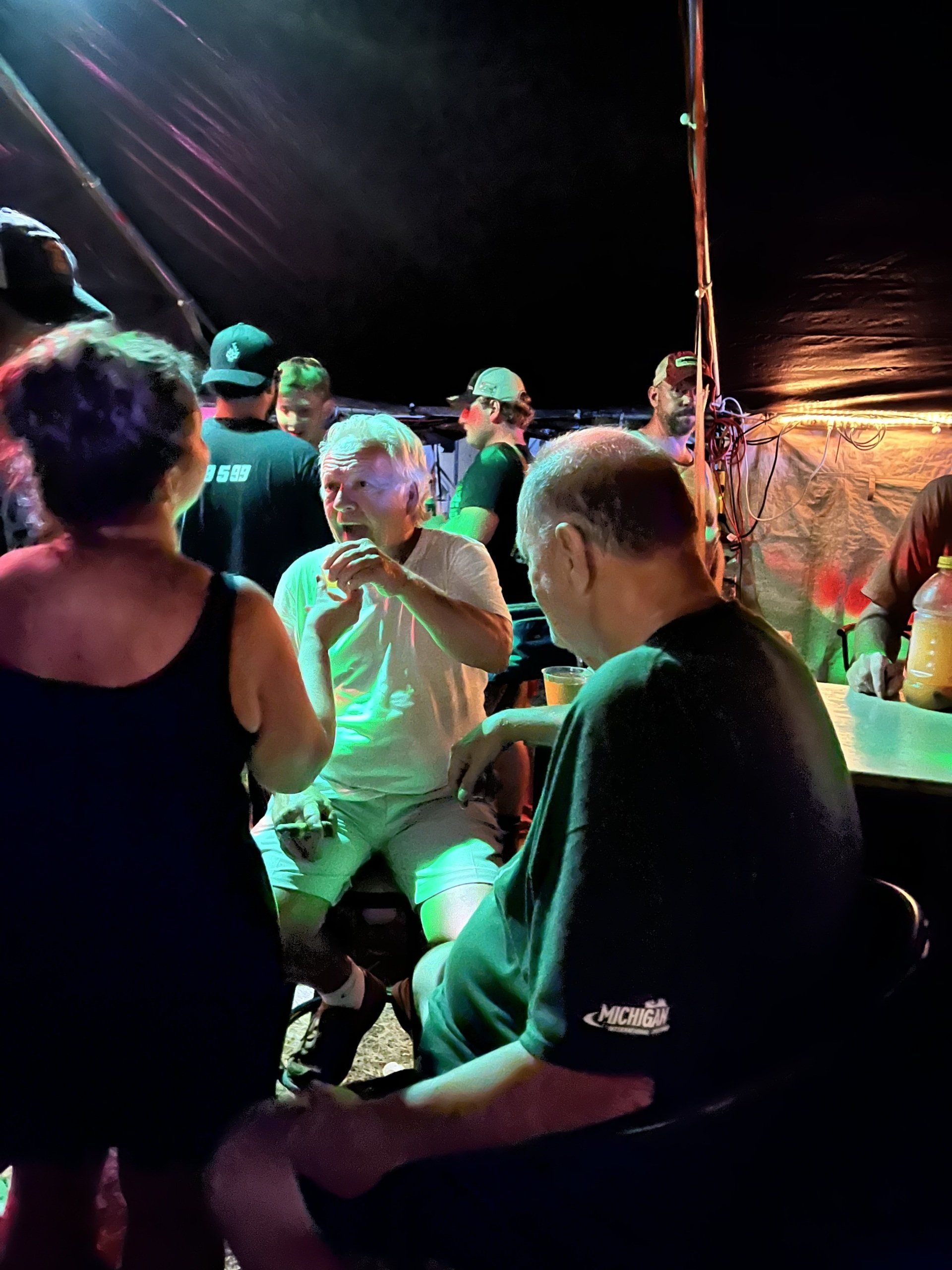 A group of people are sitting in a dark room talking to each other