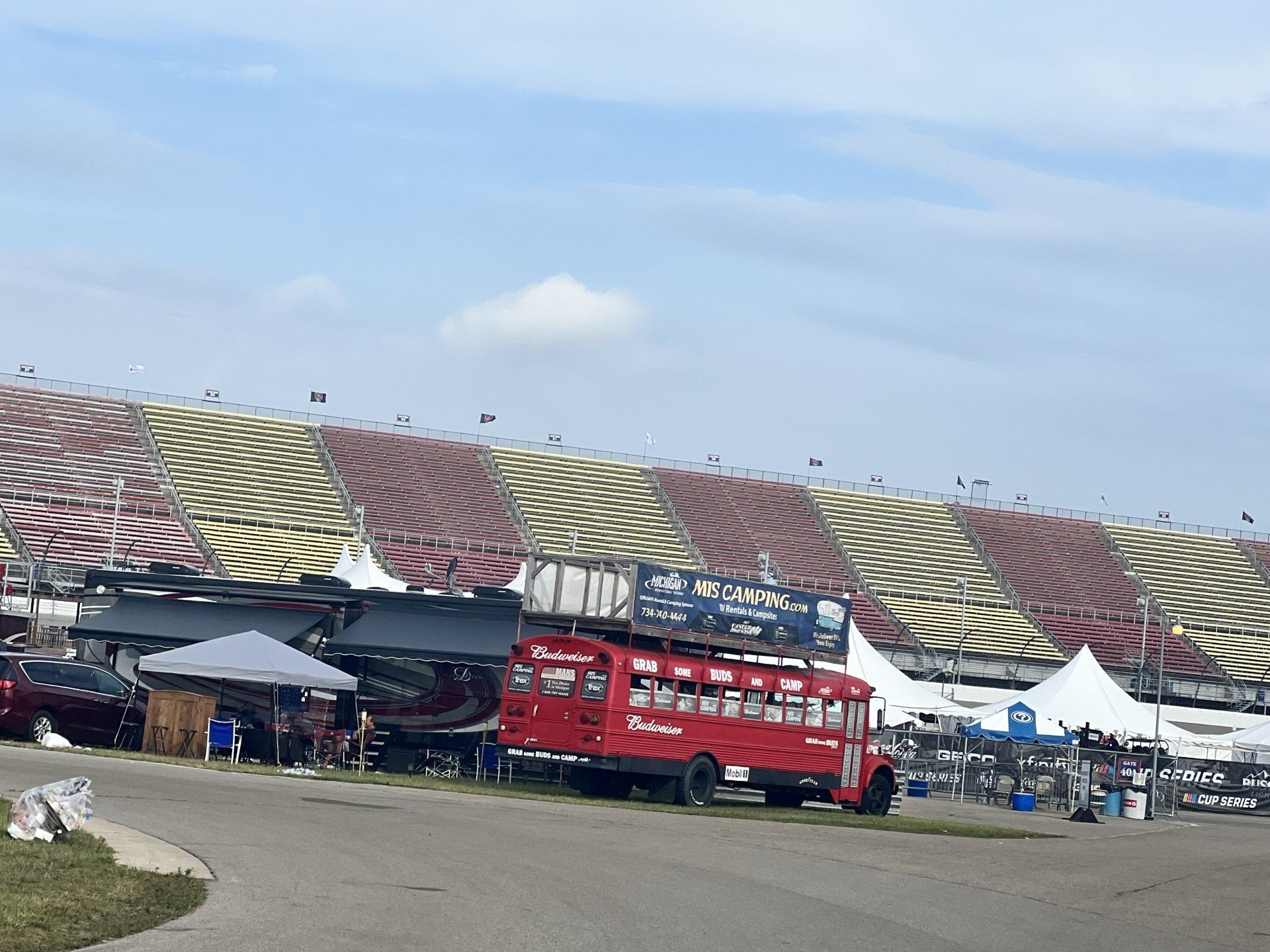 A red double decker bus is parked in front of a stadium.