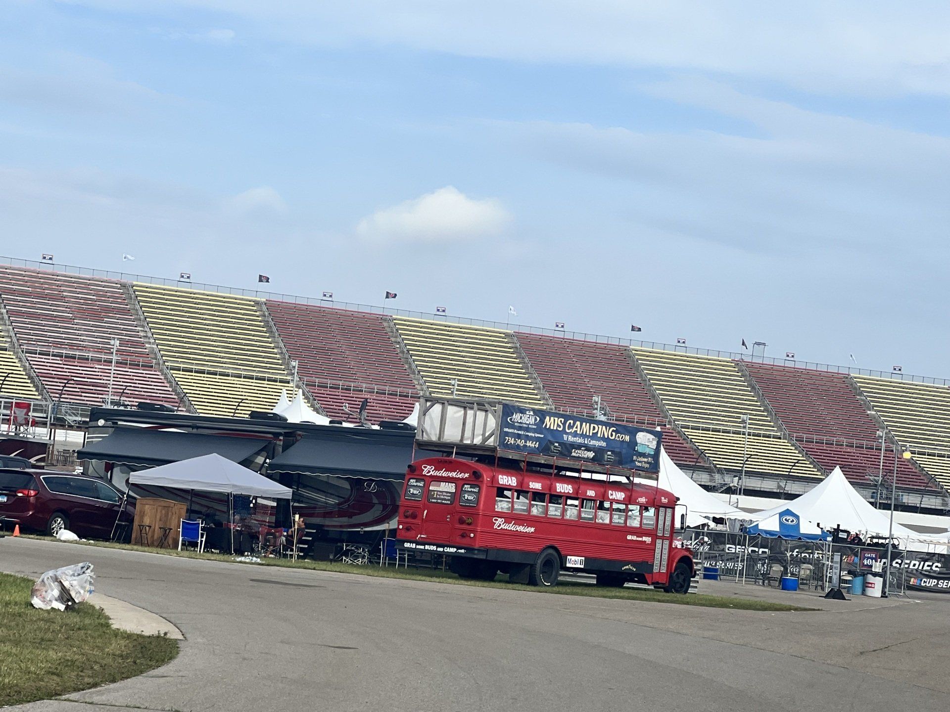 A red double decker bus is parked in front of a stadium