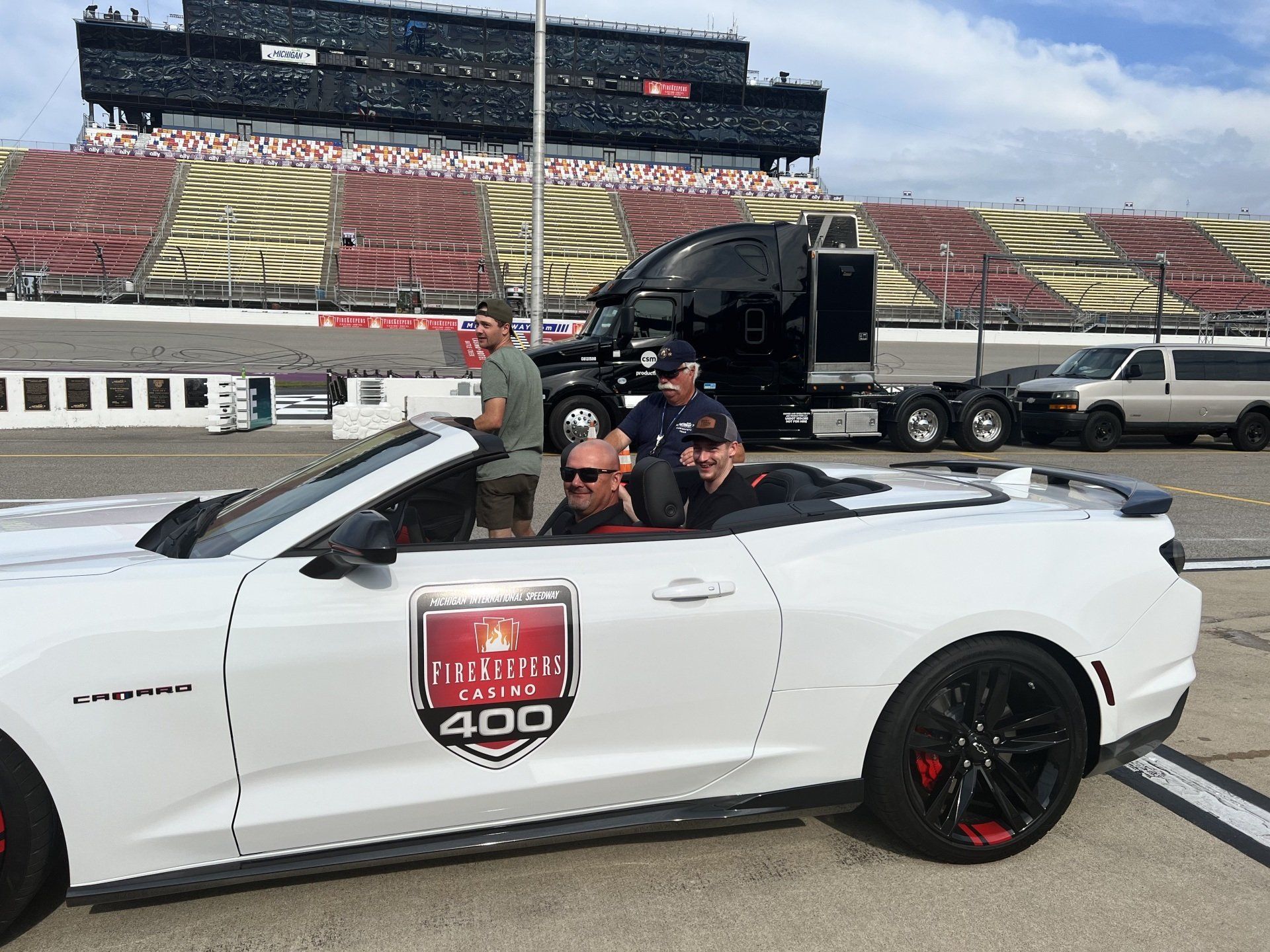 A group of people are sitting in a white convertible car.