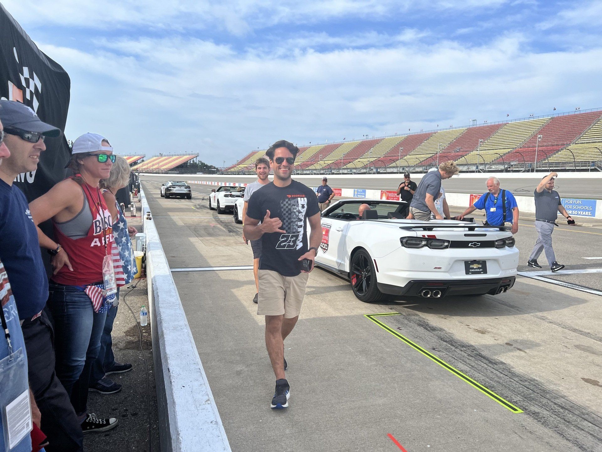 A man walking on a race track next to a white car