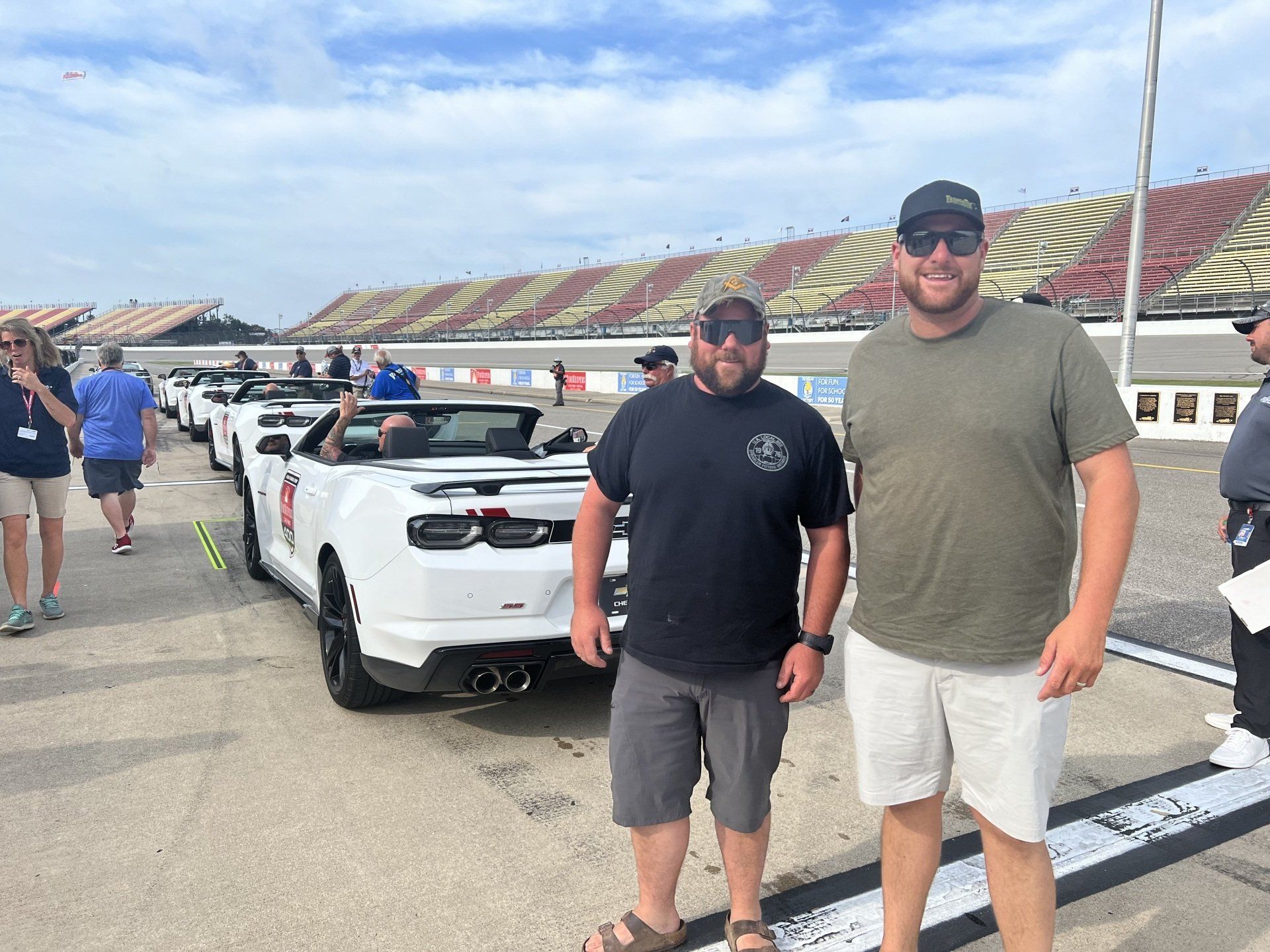 Two men are standing in front of a row of sports cars