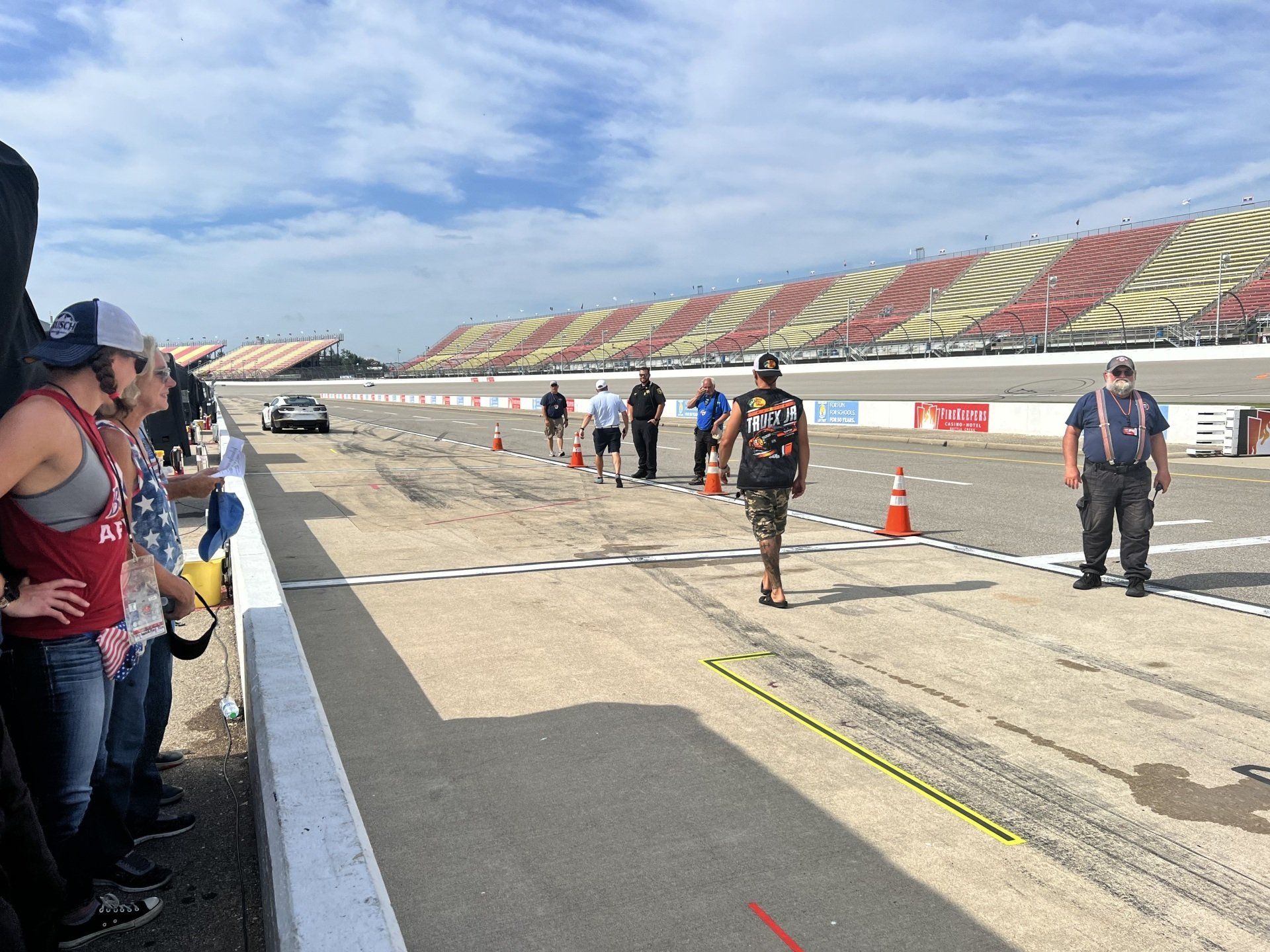 A group of people standing on a race track watching a race