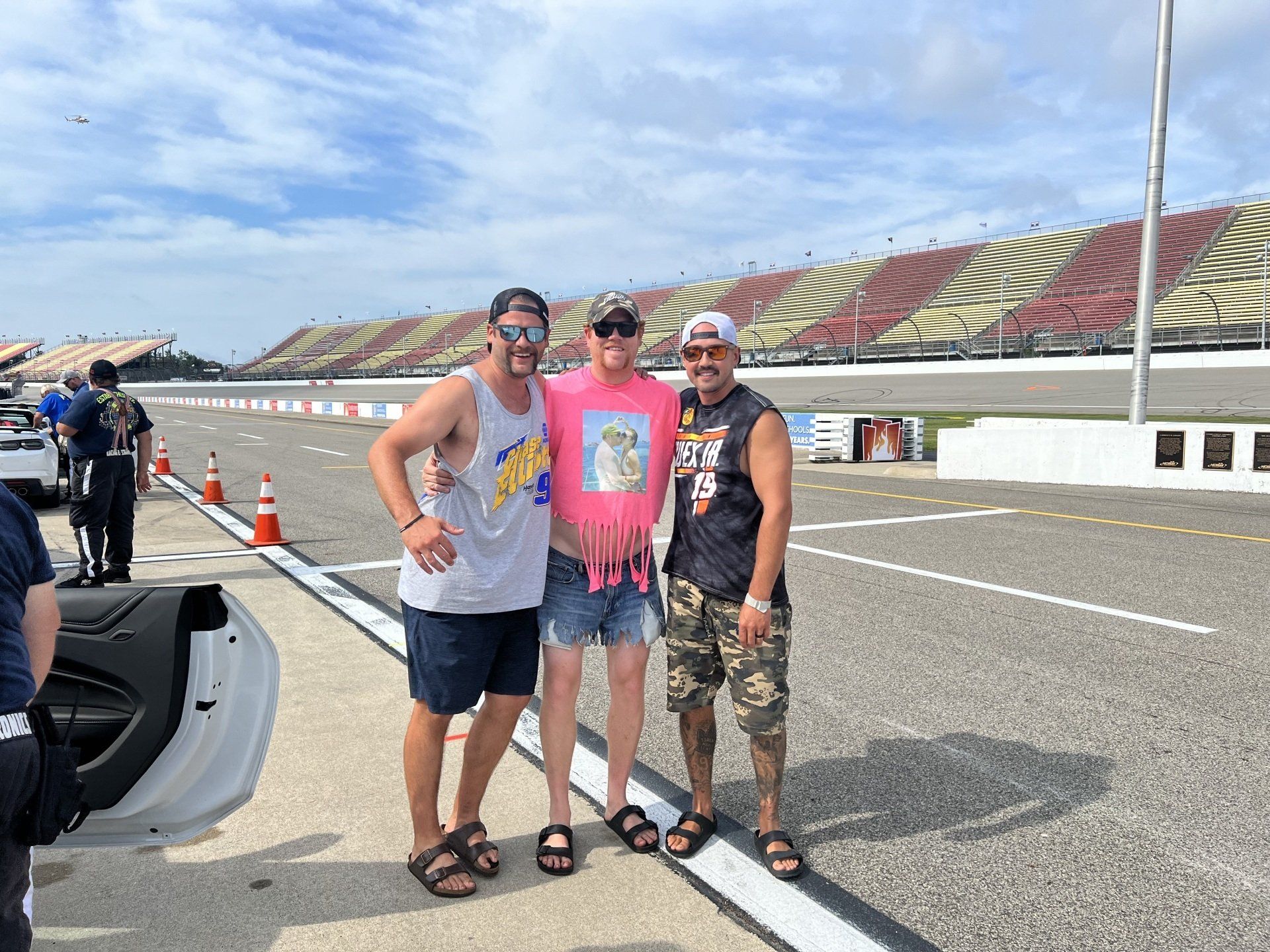 Three men are posing for a picture on a race track.
