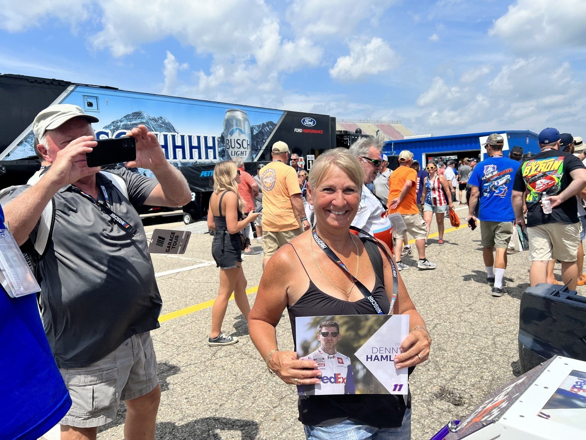 A woman is holding a picture of a man while a man takes a picture of her.